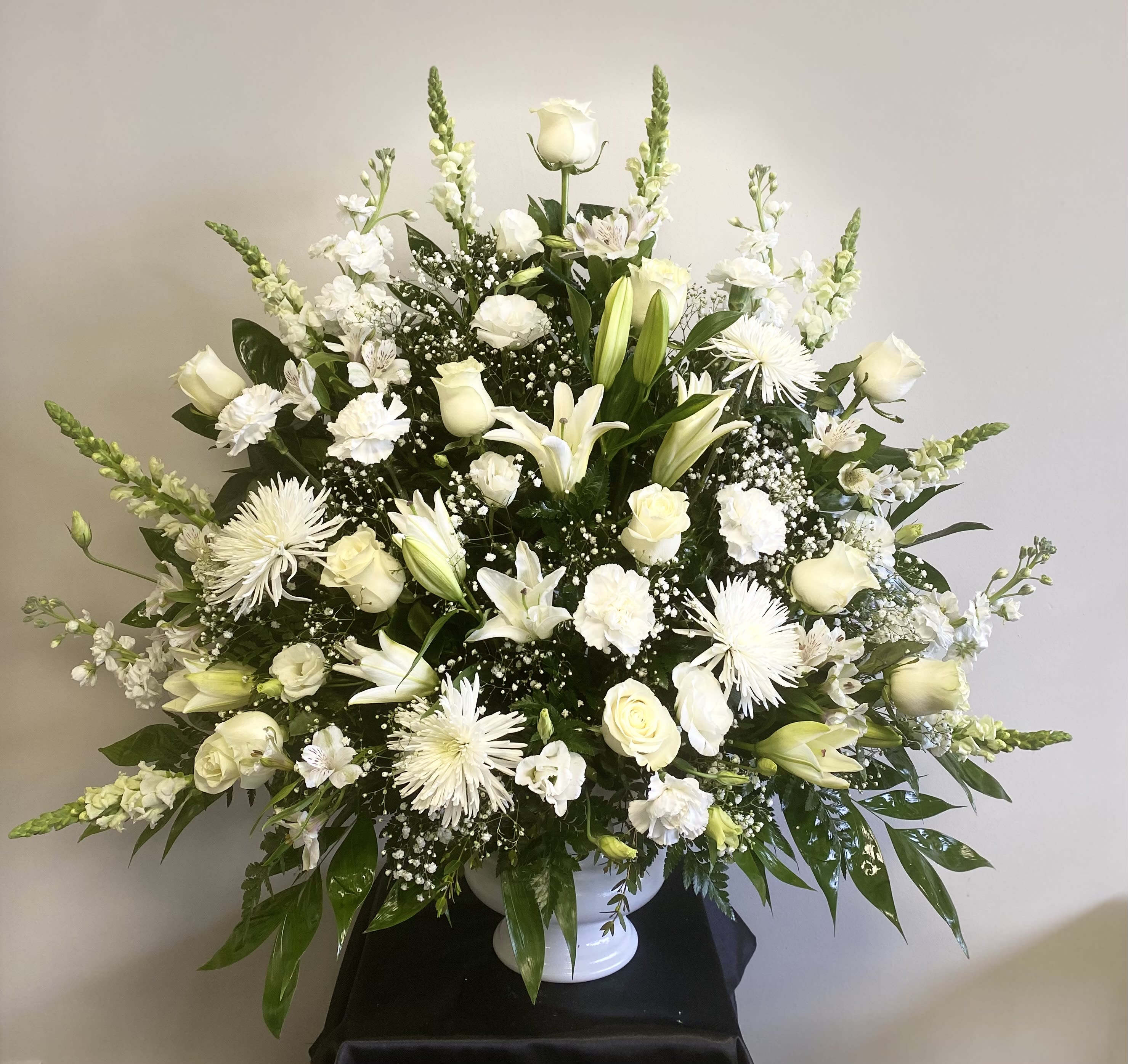 White floral arrangement in a white pedestal vase