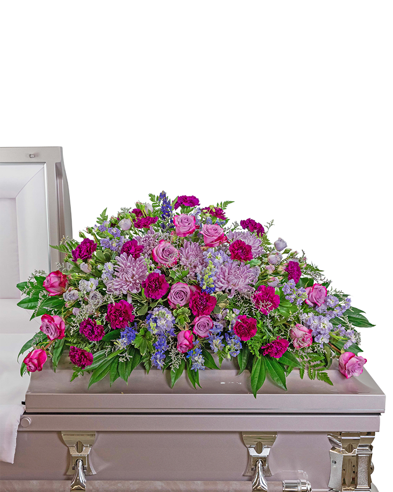 Large pink and purple floral casket spray on a light-colored casket
