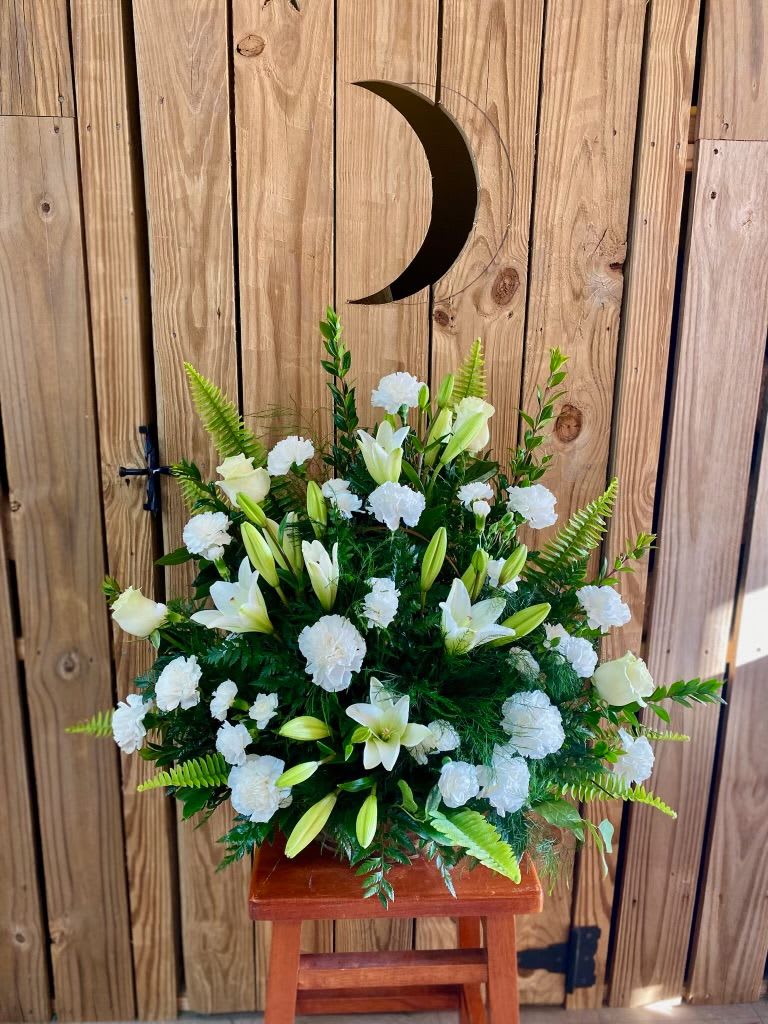 White lilies and carnations in a standing floral arrangement