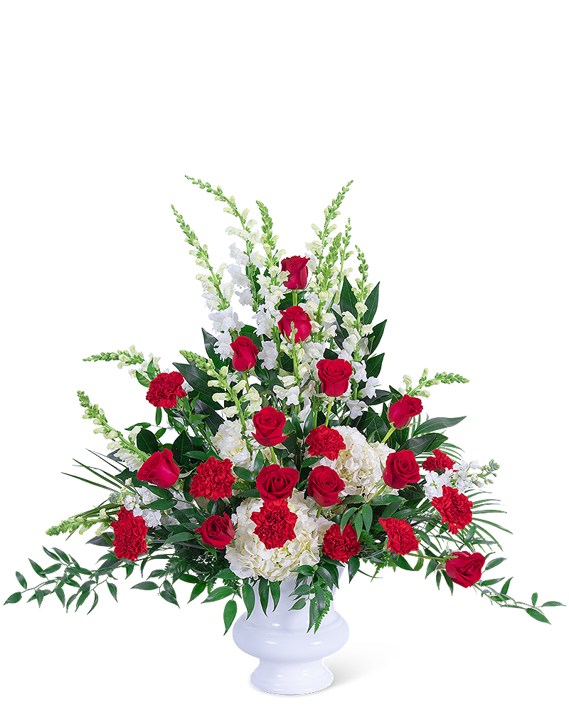 Red roses and white flowers arranged in a white pedestal vase