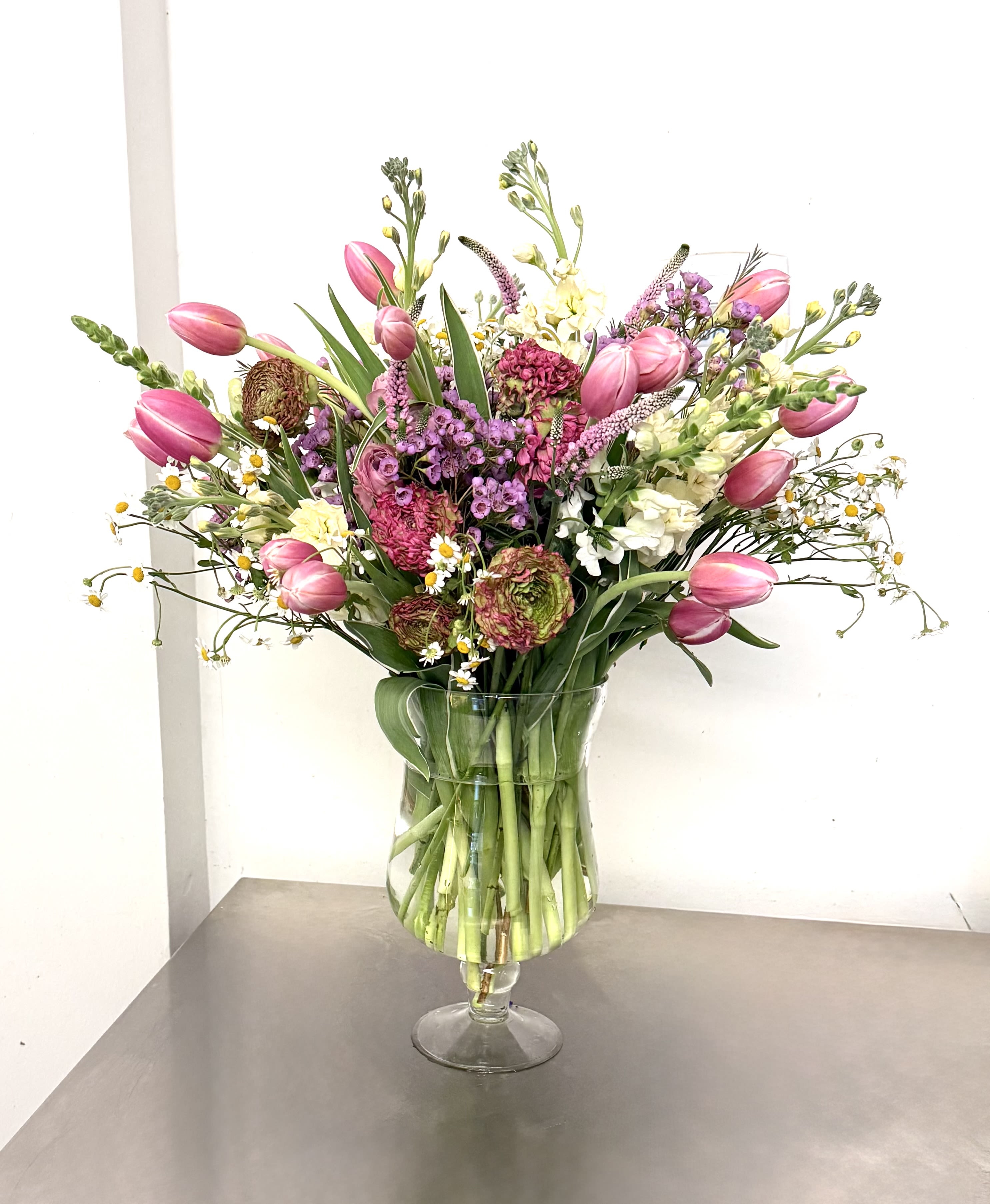 The Prancing Spring Bouquet  - Celebrate the season with an artfully designed arrangement that captures the essence of a fresh spring garden. This vibrant, natural-style bouquet features a rich tapestry of textures and soft pastel hues, blending modern elegance with a relaxed personality.
