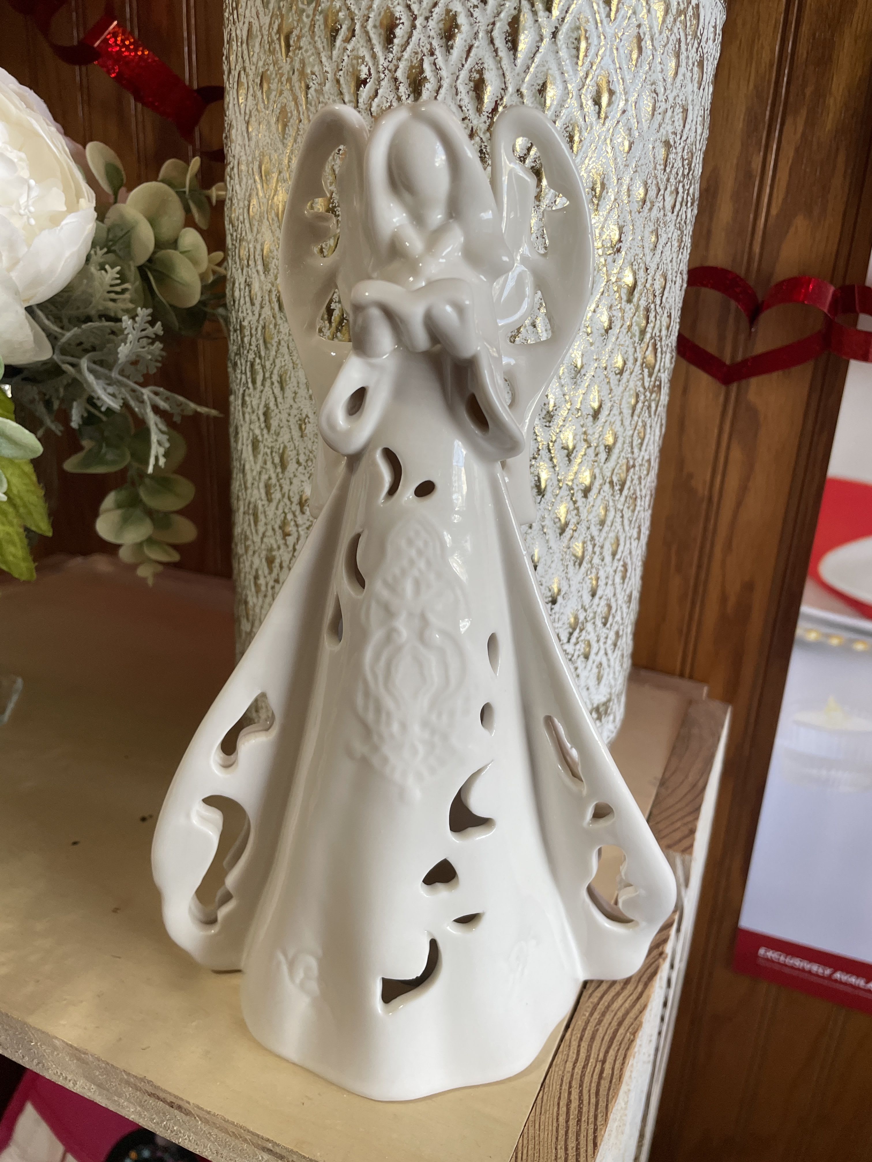Ceramic angel figurine with cutout details on a shelf