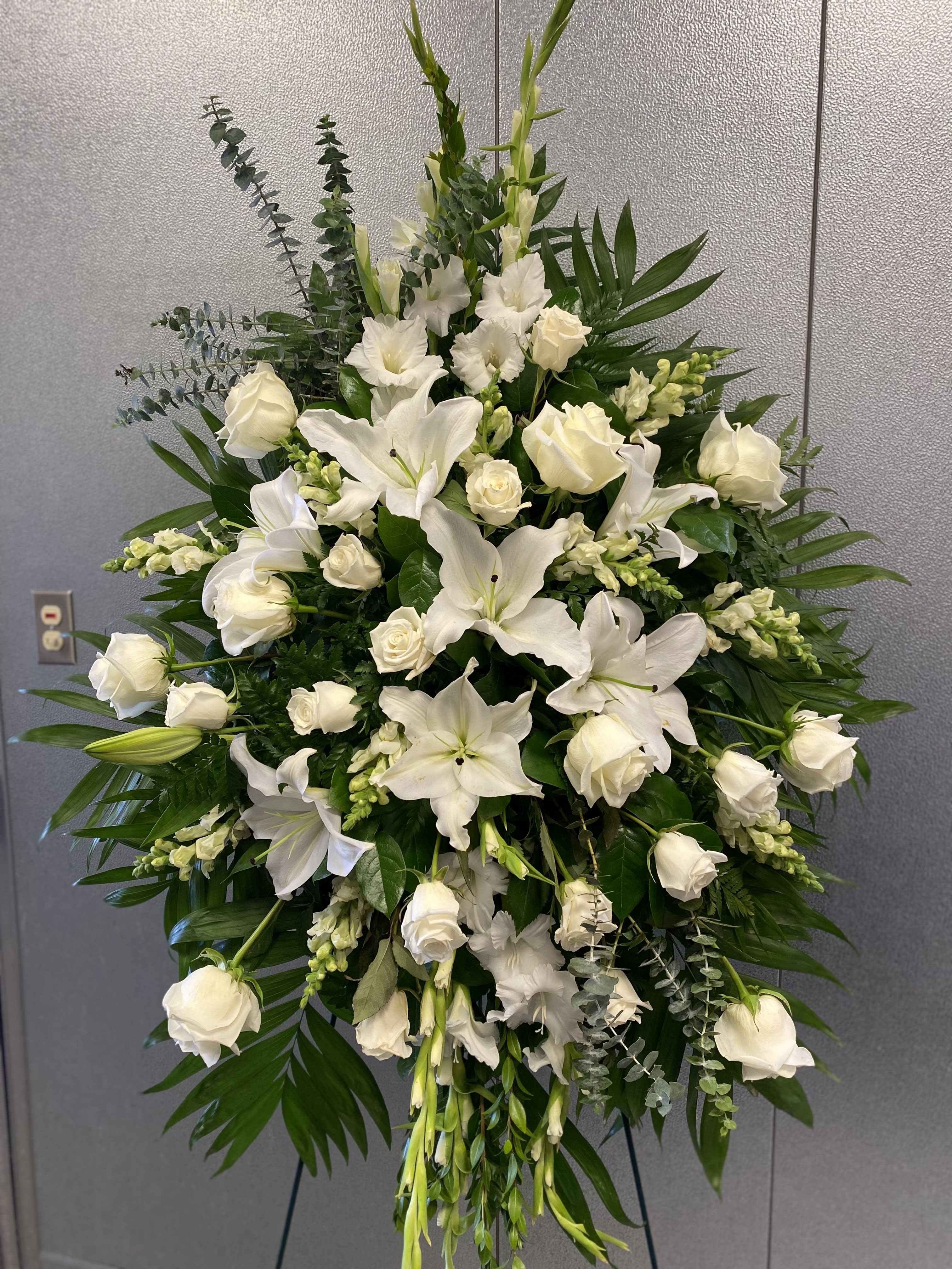 Large white floral standing spray with roses and lilies