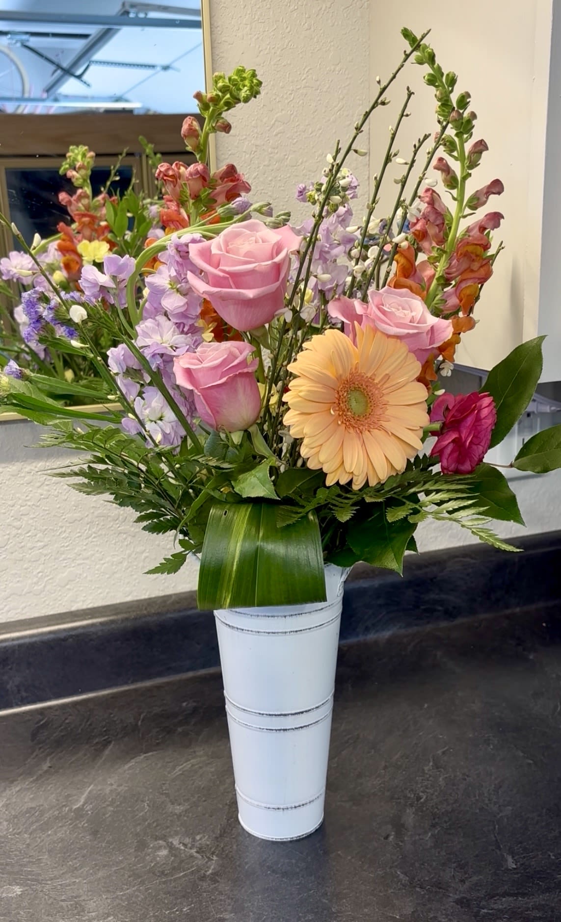 Mother's Day Special - Celebrate Mom with a vibrant mix of fresh spring flowers in full bloom. This arrangement bursts with color—peaches, pinks, and pops of lavender—creating a joyful display that’s as bright and uplifting as she is.