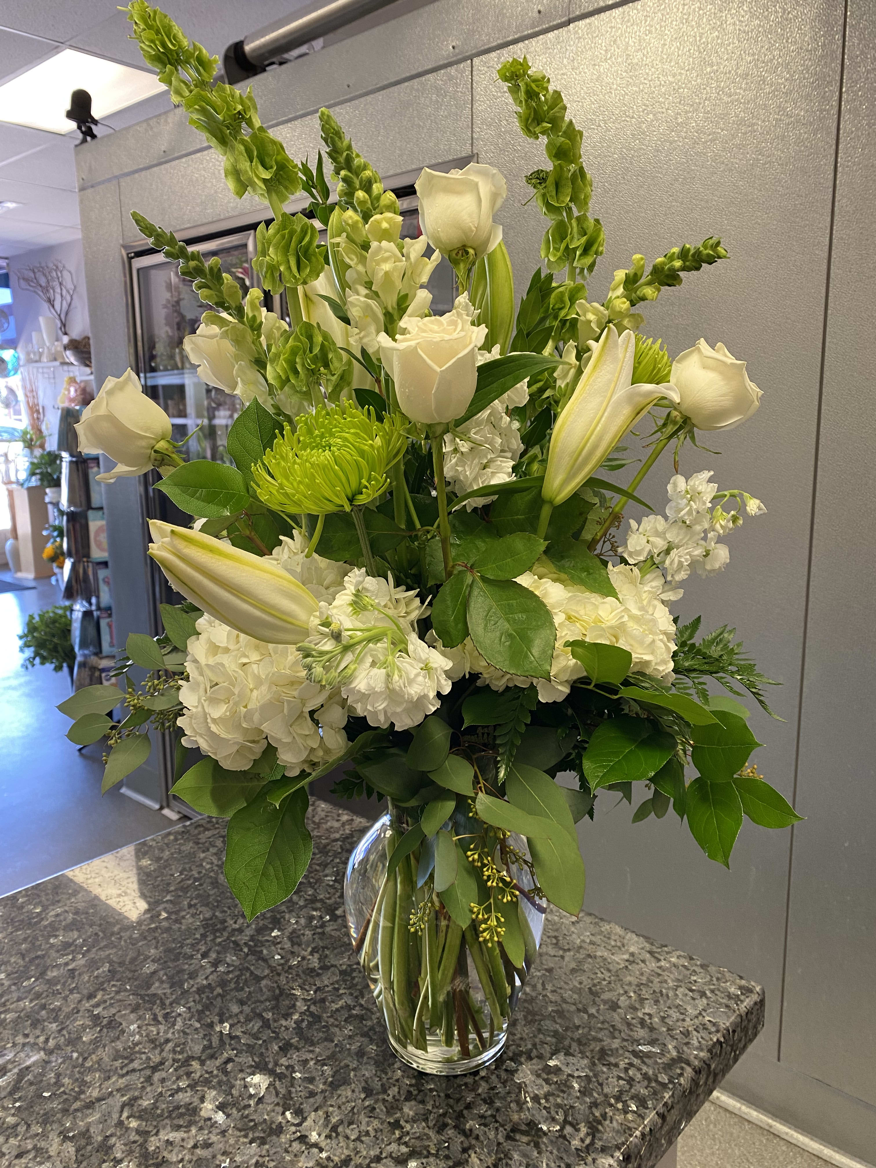 White roses and lilies arranged in a clear glass vase