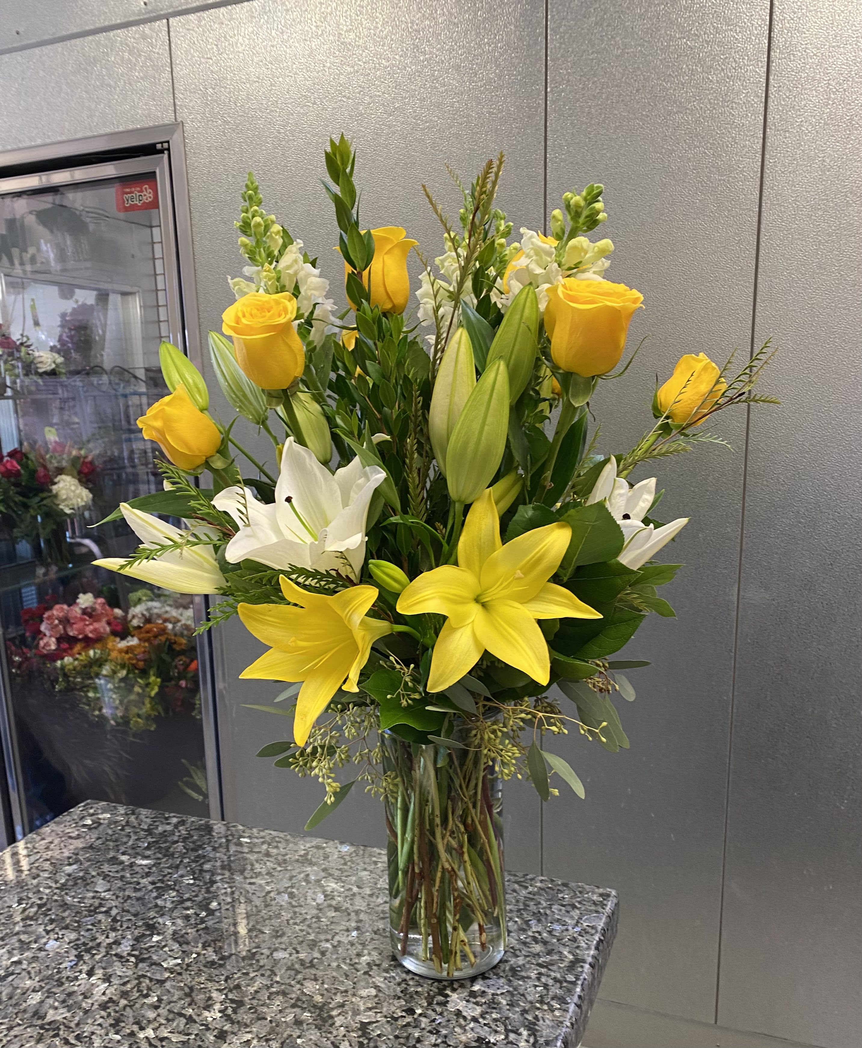 Yellow roses and white lilies in a clear glass vase