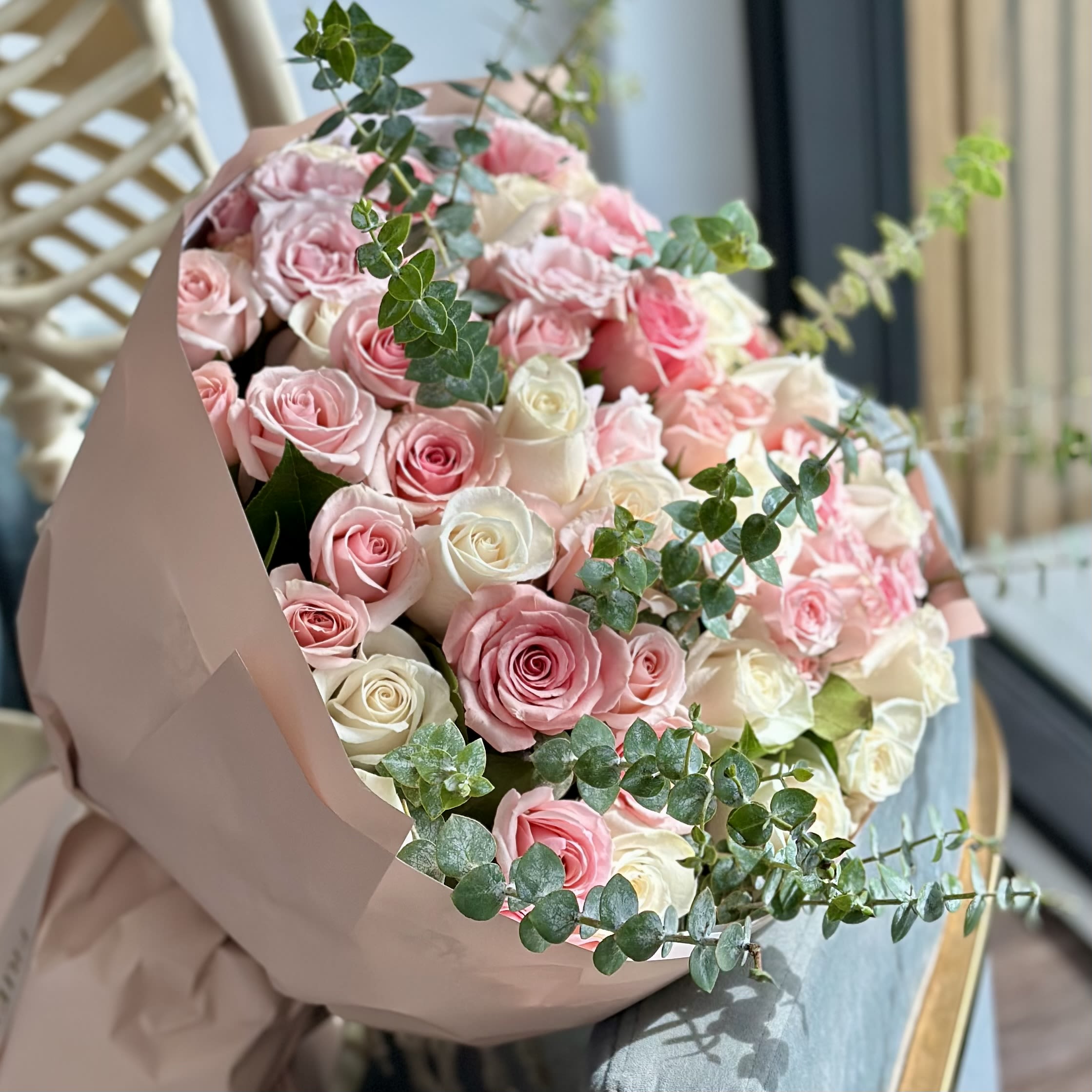 Bouquet of pink and white roses wrapped in blush paper