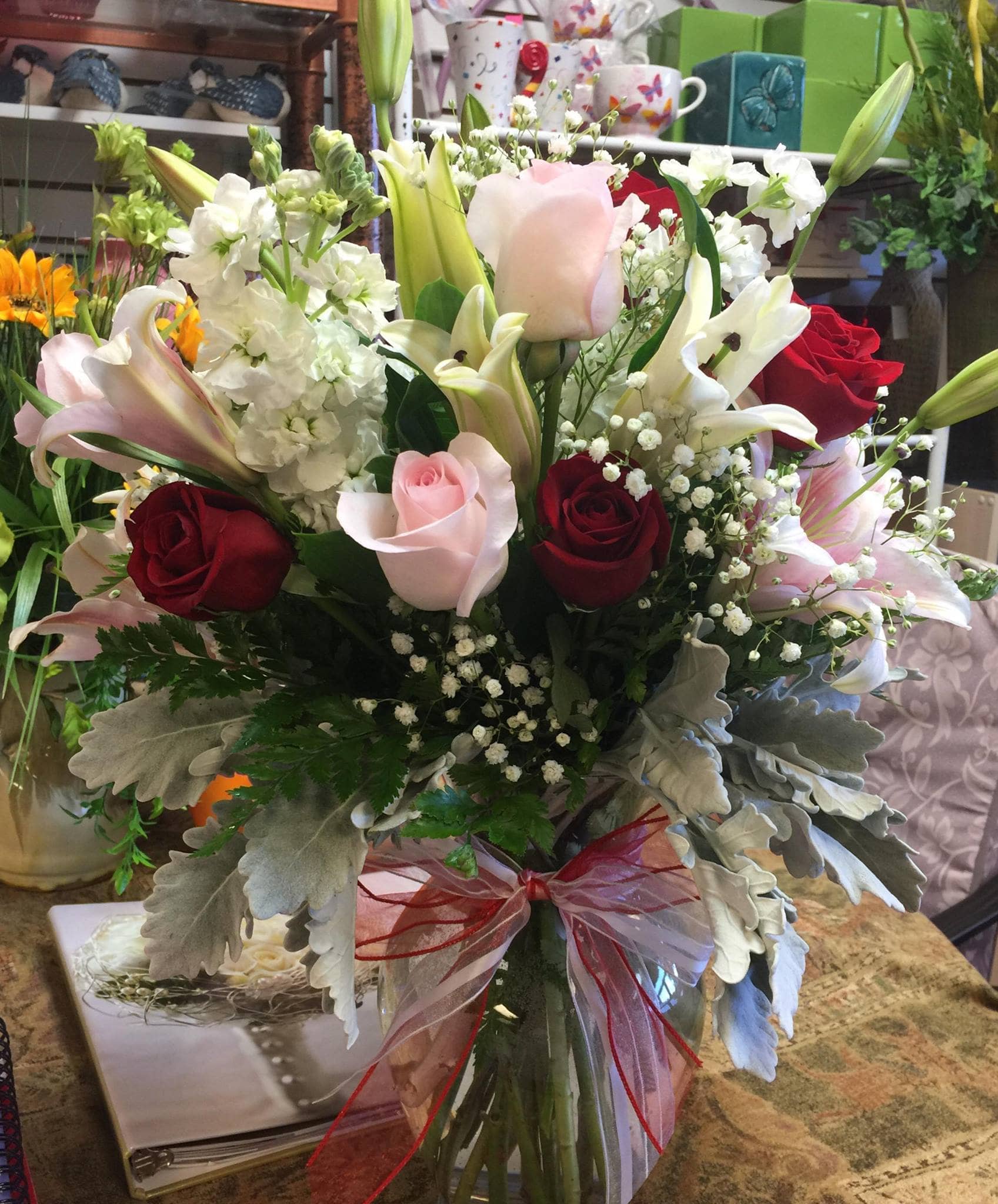 Bouquet of red and pink roses with white lilies in a glass vase