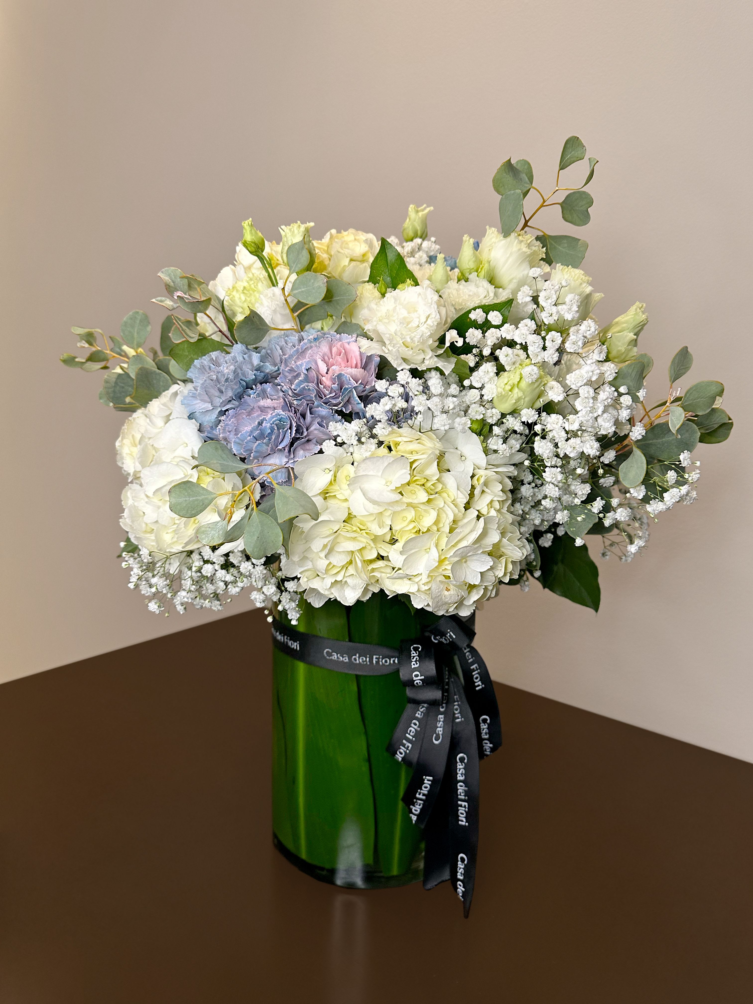 Bouquet of white and pale blue flowers in a green glass vase