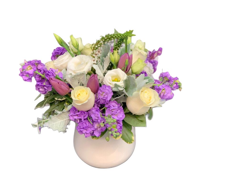 Purple and cream floral arrangement in a round vase