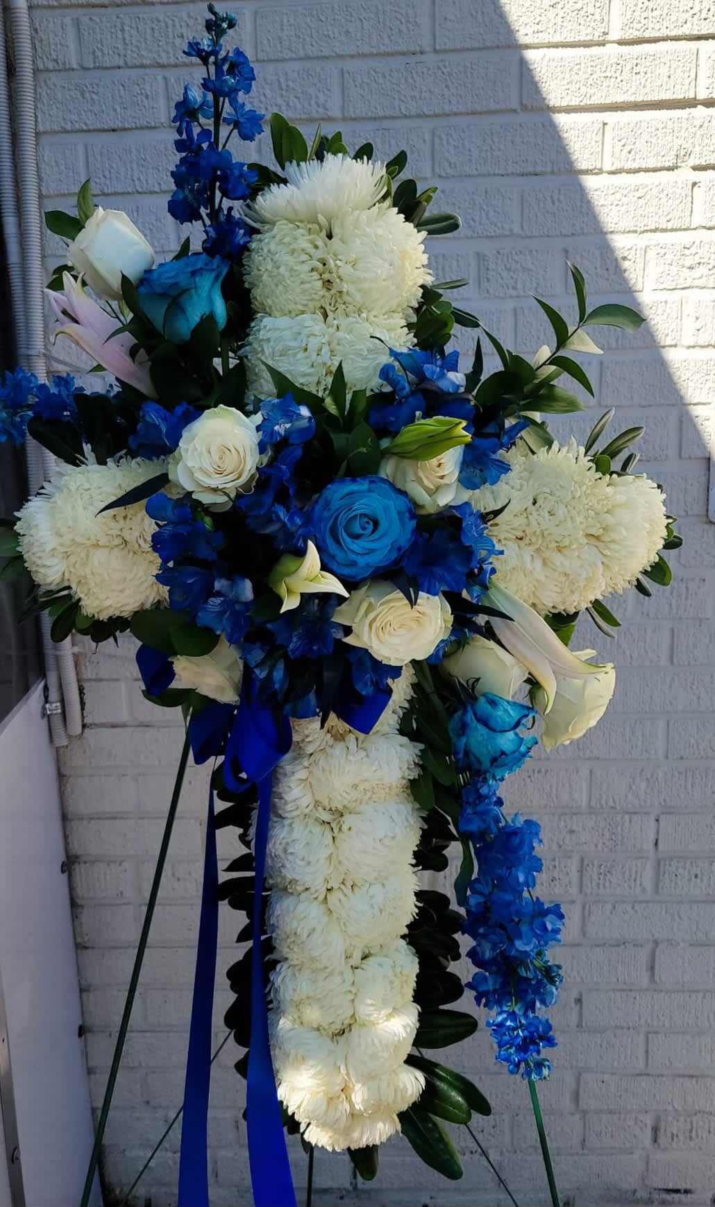 Cross Stand #1 - it is made with: 30 mums 3 blue roses 6 white roses 2 white lilies 4 blue stock 6 blue alstroemeria greens  