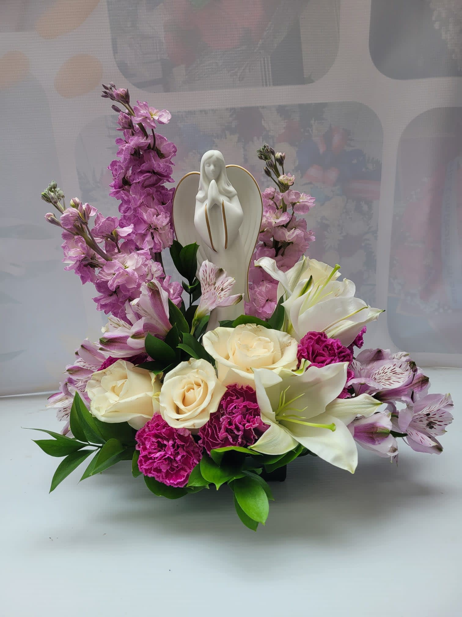 Funeral Bouquet #1 - it is made with: 1 white Lilie 3 white roses 3 lavender/purple alstroemeria 3 lavender stock 3 purple carnation ceramic angel greens 