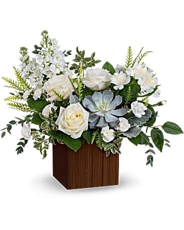 White roses and pale blue succulents in a wooden cube vase