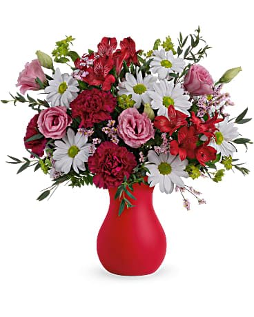 Mixed bouquet of red and pink flowers in a red vase