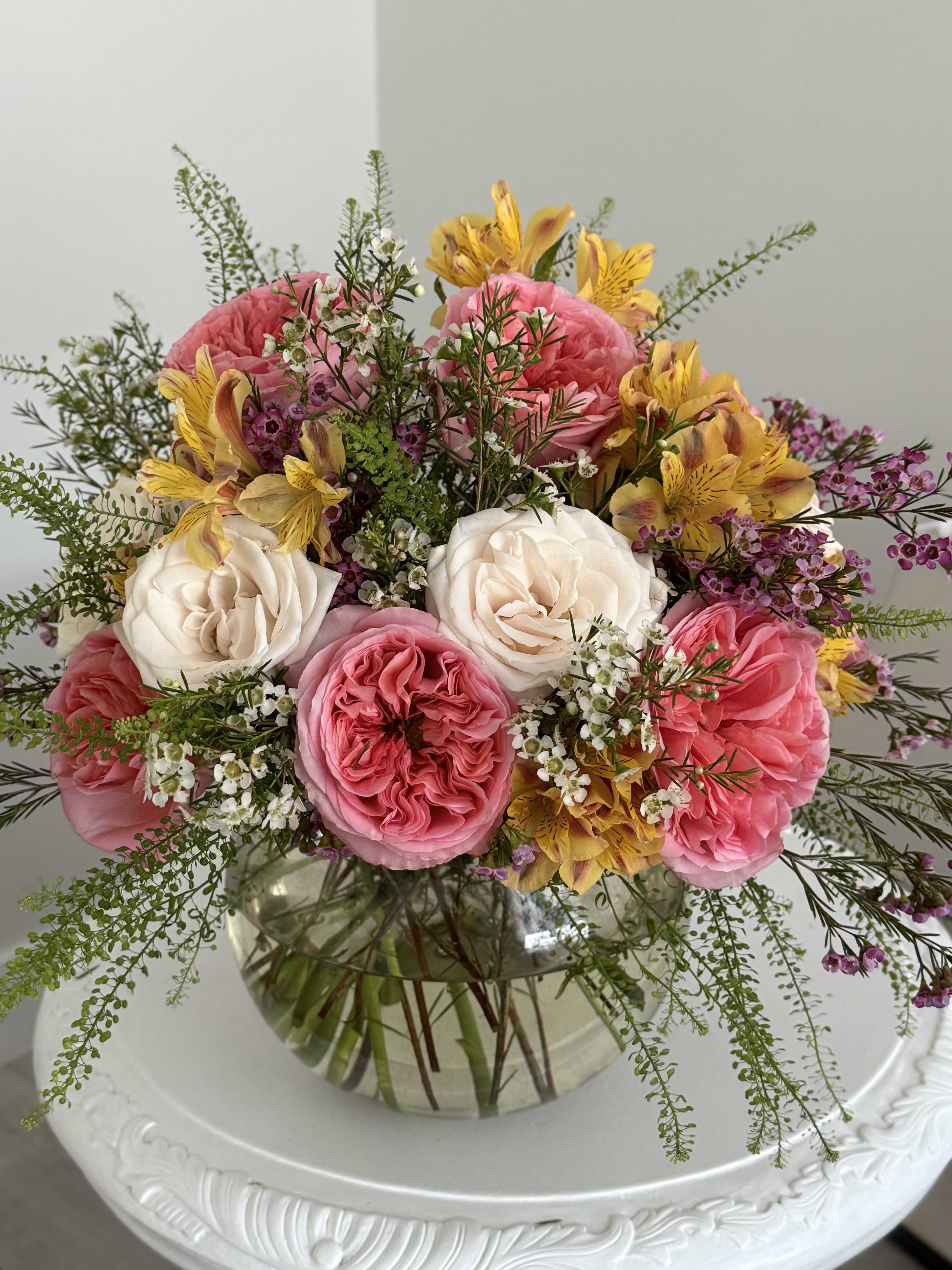 Pink and white roses with yellow flowers in a glass vase