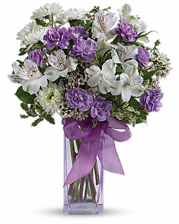 Purple and white mixed bouquet in a clear square vase with a purple ribbon