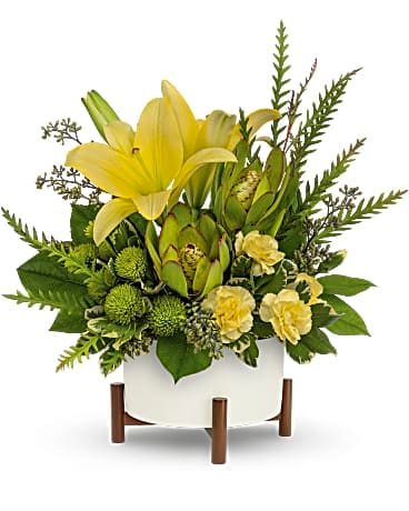 Yellow lilies and green blooms in a white planter on wooden legs