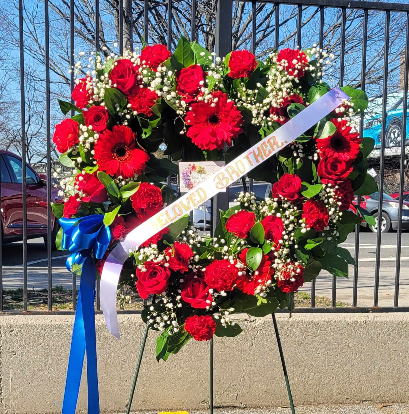 Standing Hearth Spray #1 - it is made with: 5 red gerberas 12 red roses 20 red single carnations greens baby breath blue ribbon white bow banner  stand.