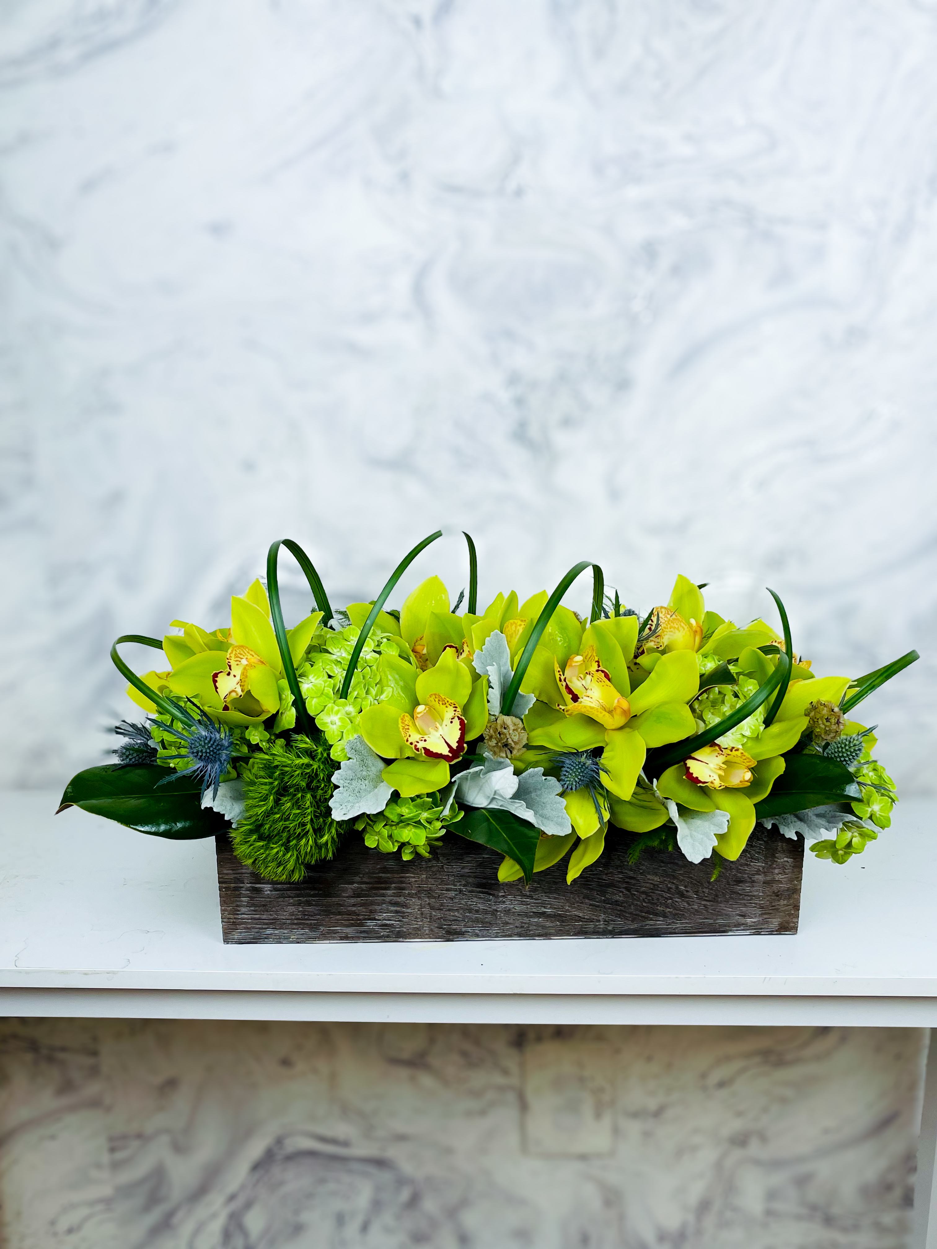 Rectangular arrangement of lime-green orchids in a wooden box