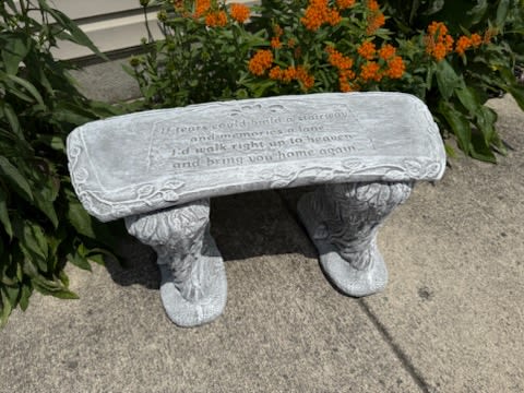 Stone bench with engraved text in front of orange flowers