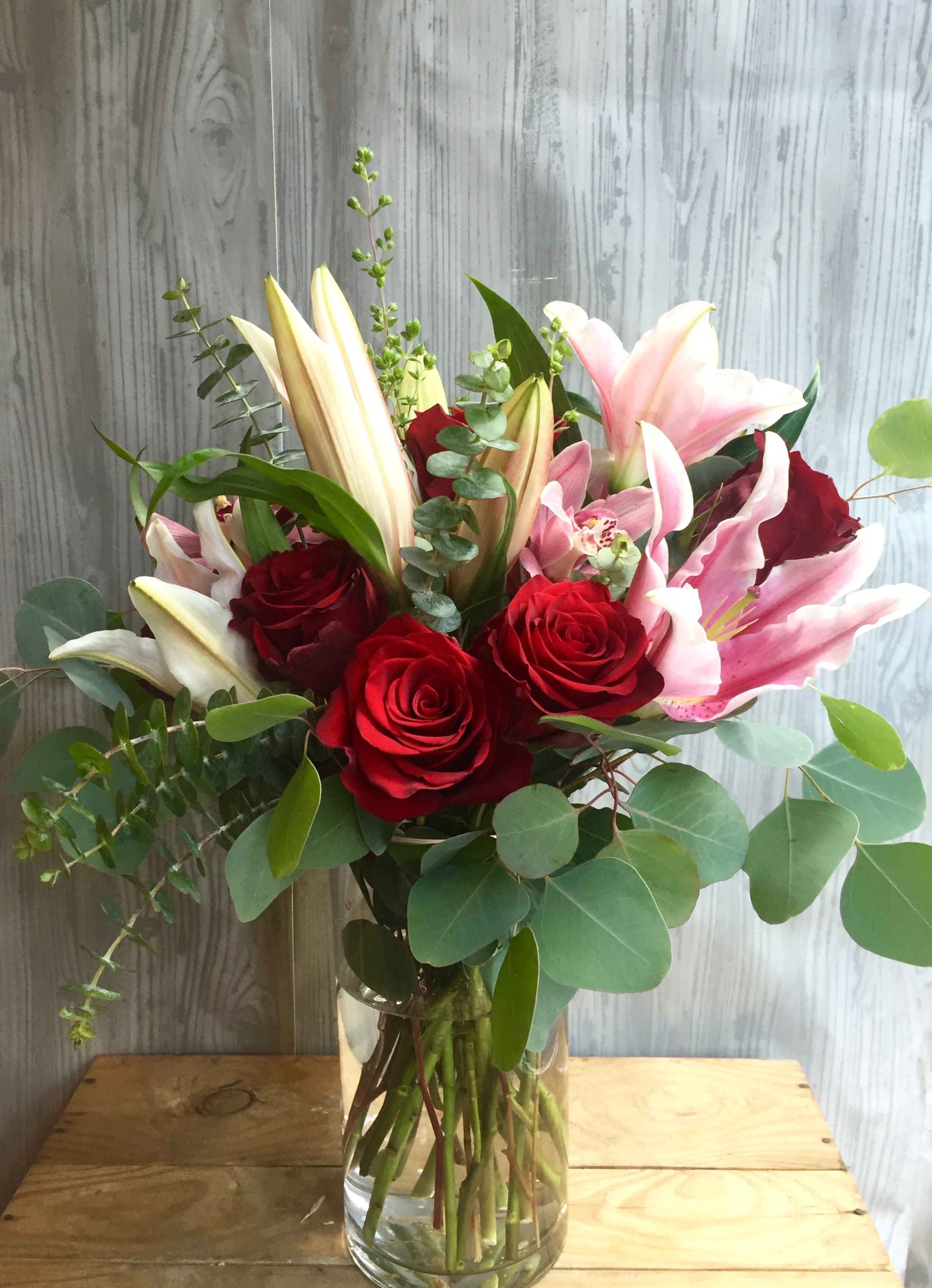 Bouquet of red roses and pink lilies in a clear glass vase