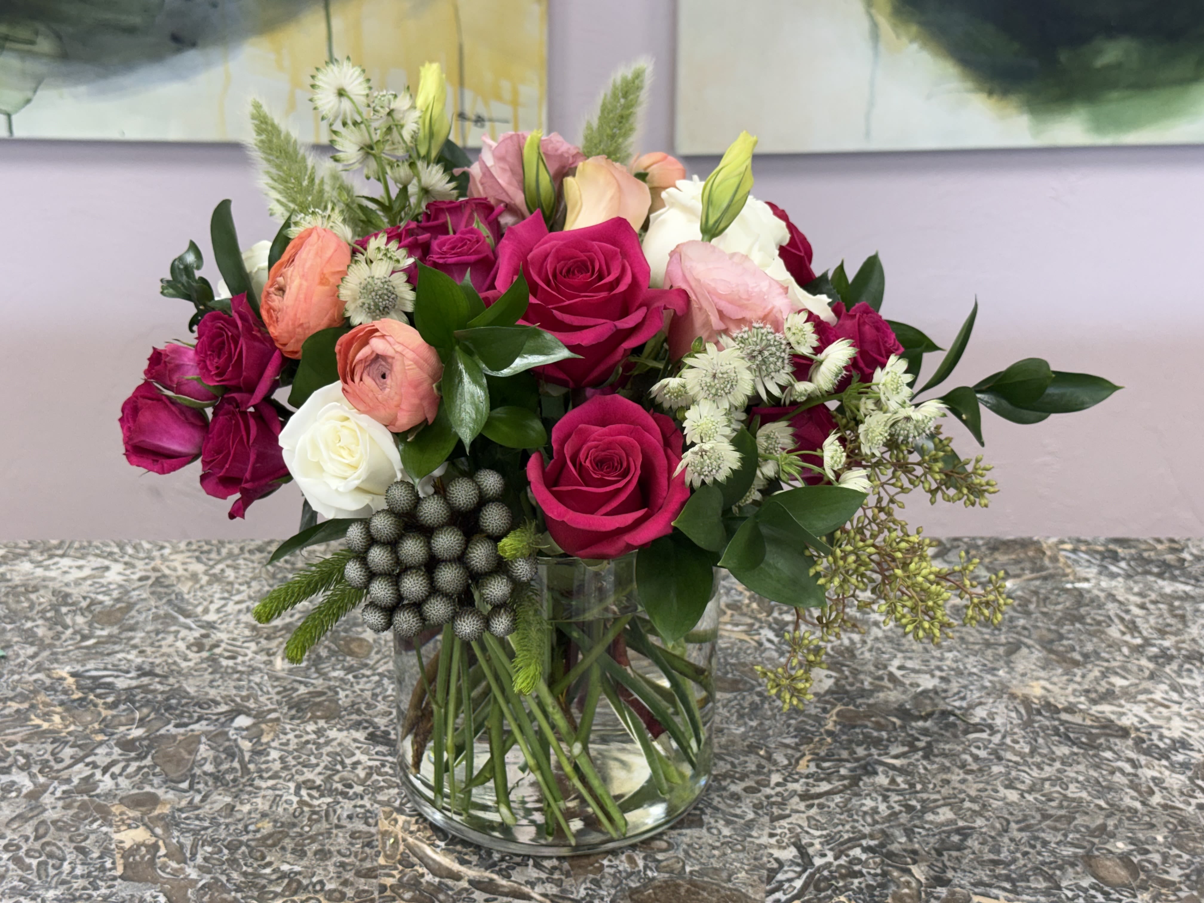Rosé Posy - A lush cluster of hot pink, white and peach blooms makes this flower arrangement a beautiful choice for an anniversary bouquet, birthday gift, or a "thinking of you" surprise. The Rosé Posy arrangement centers on roses that give a soft focal point, while ranunculus blossoms and airy white filler flowers create delicate layers so the recipient feels truly celebrated at first glance.  This is the kind of bouquet that makes someone feel seen on a special day or brightens an ordinary afternoon; it's equally suited to anniversaries, birthdays, or as a warm congratulatory gesture. Vase included-no extra arranging required-and simple care (fresh water and a cool spot away from direct sun) will keep the blooms looking lovely for days.  *Flowers are subject to substitutions of equal value.
