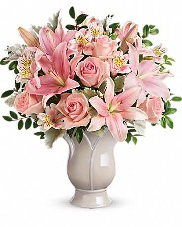 Pink lilies and roses arranged in a white vase