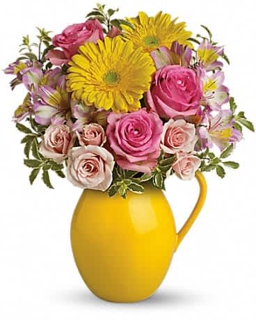 Pink roses and yellow daisies in a yellow pitcher vase