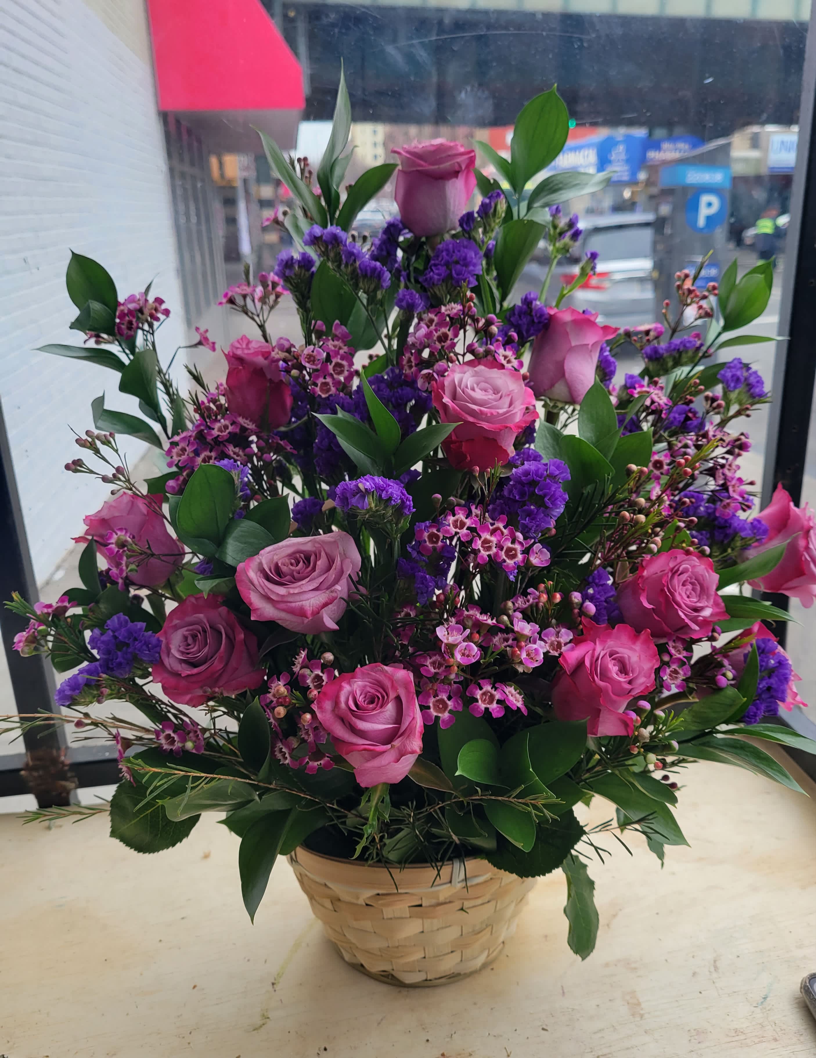 Basket arrangement of pink and purple roses with small filler flowers