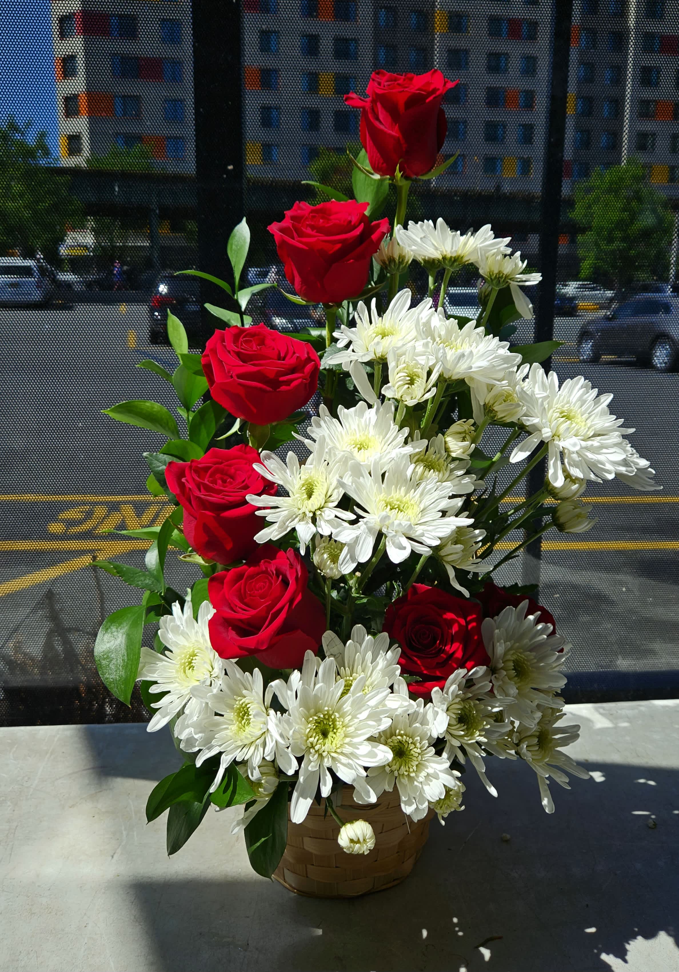Basket arrangement of red roses and white daisies