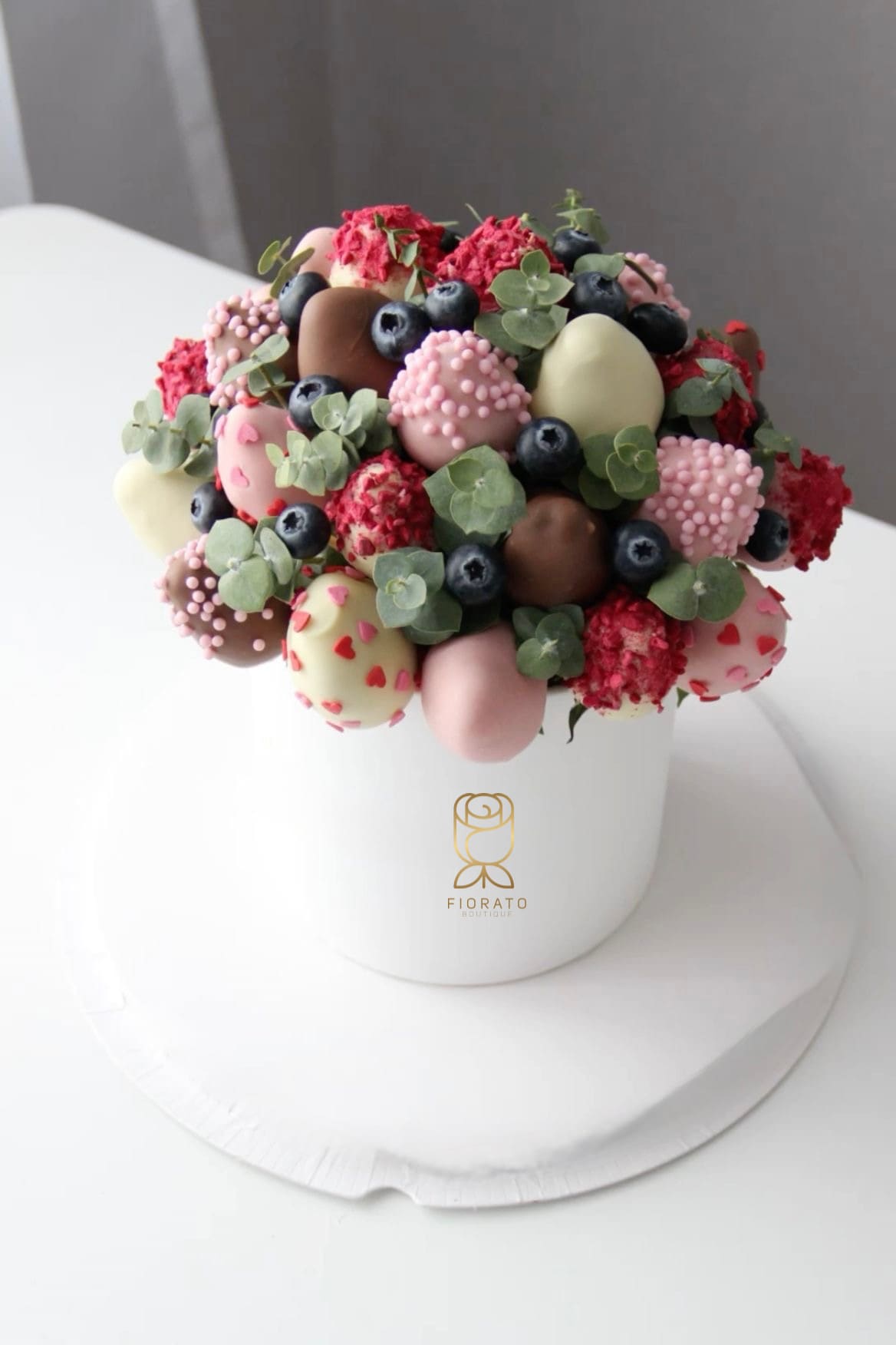 Chocolate-covered strawberries and blueberries in a white hatbox