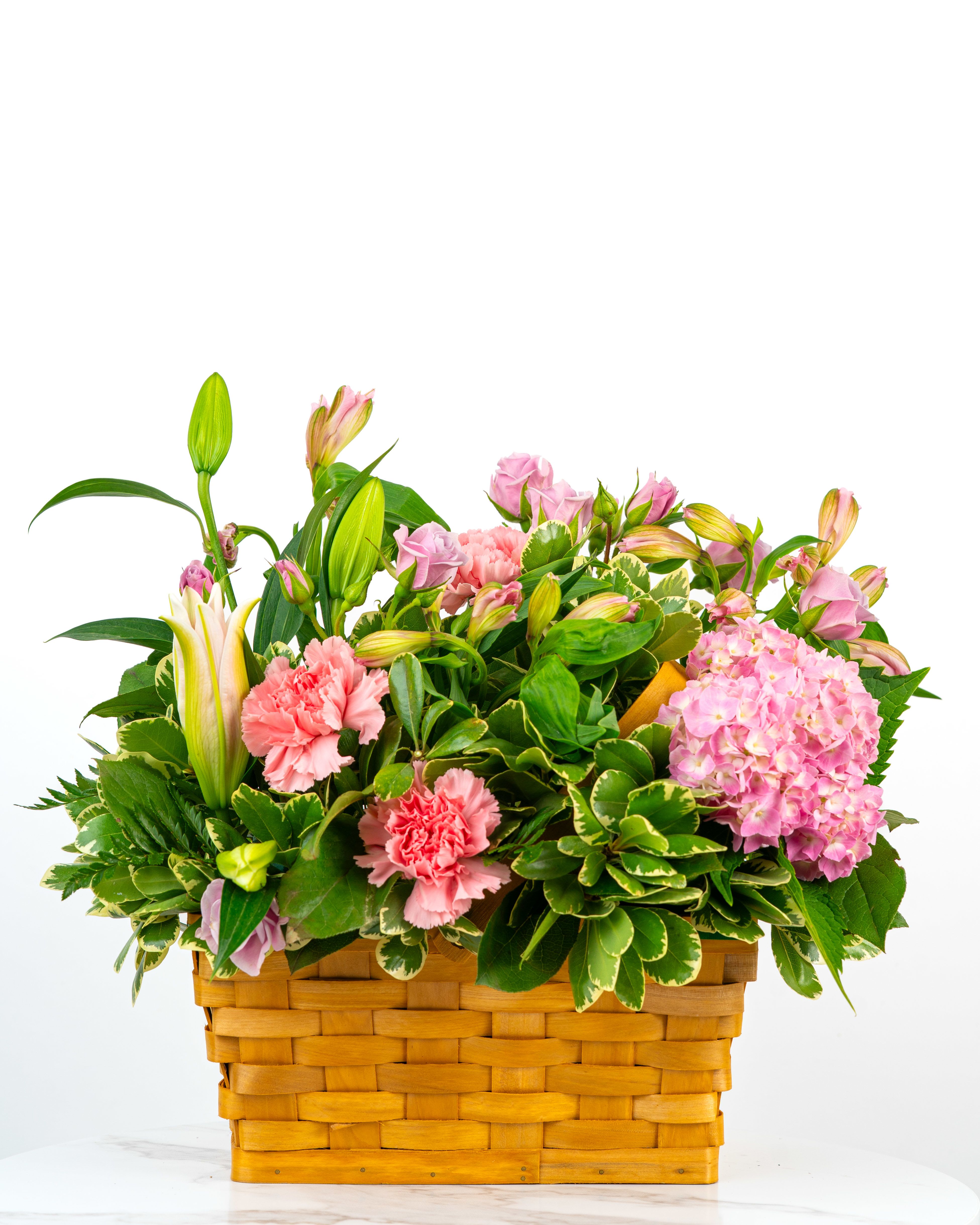 Pink flowers and lilies arranged in a woven basket
