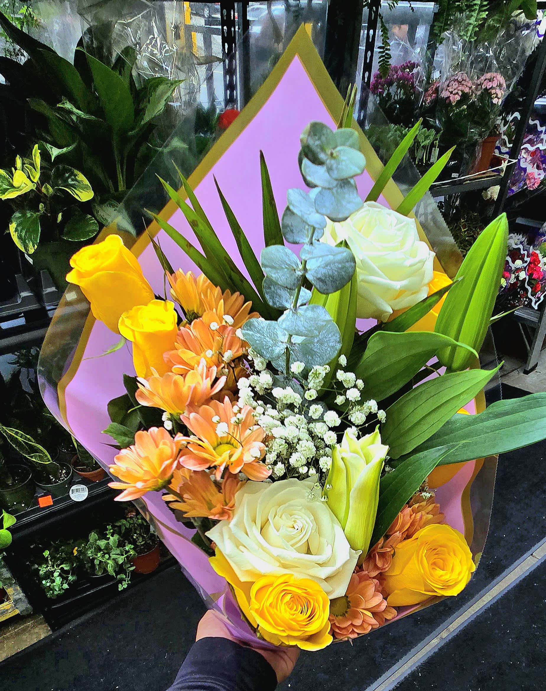 Bouquet of yellow and white roses with orange daisies and blue eucalyptus