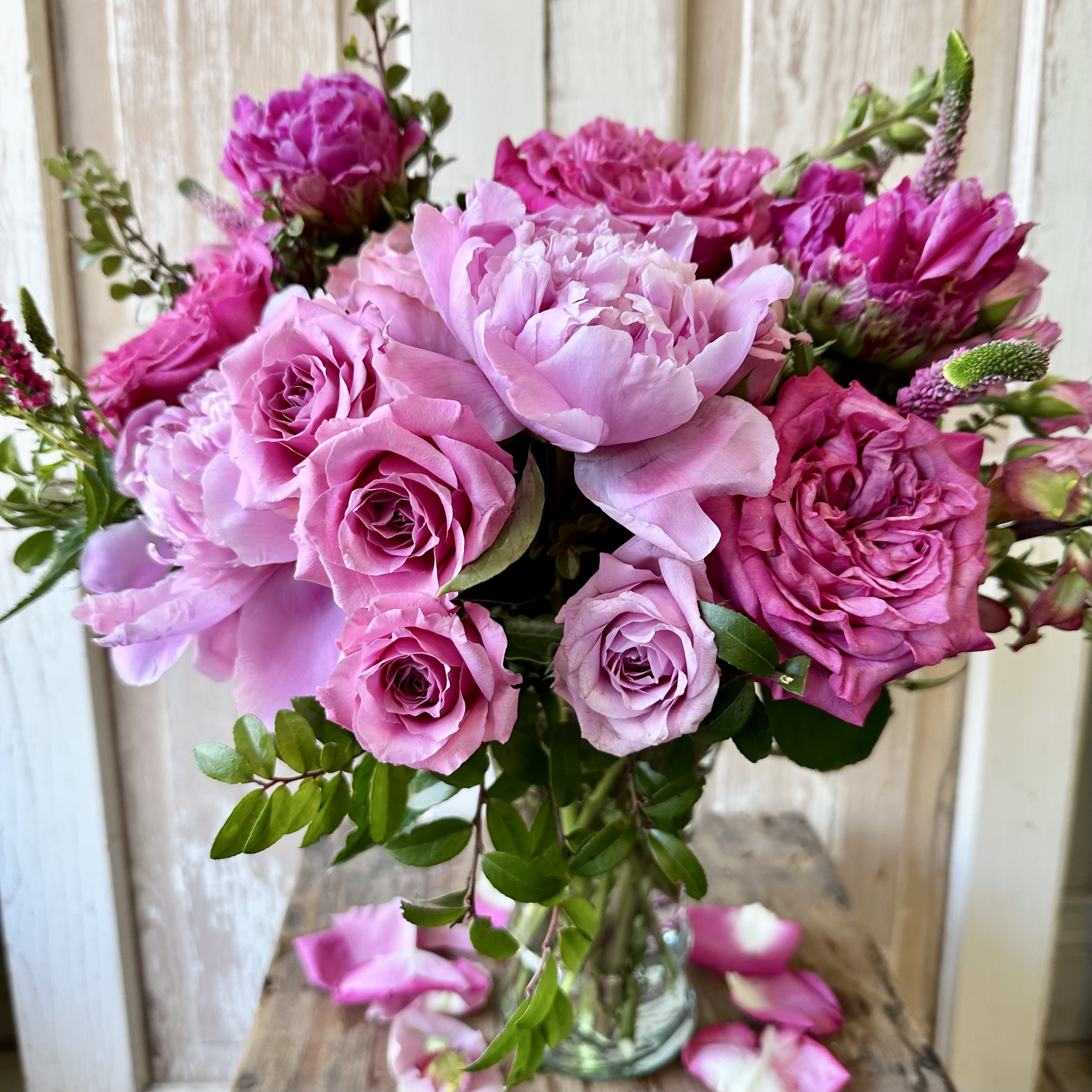 Pink roses and peonies arranged in a clear glass vase