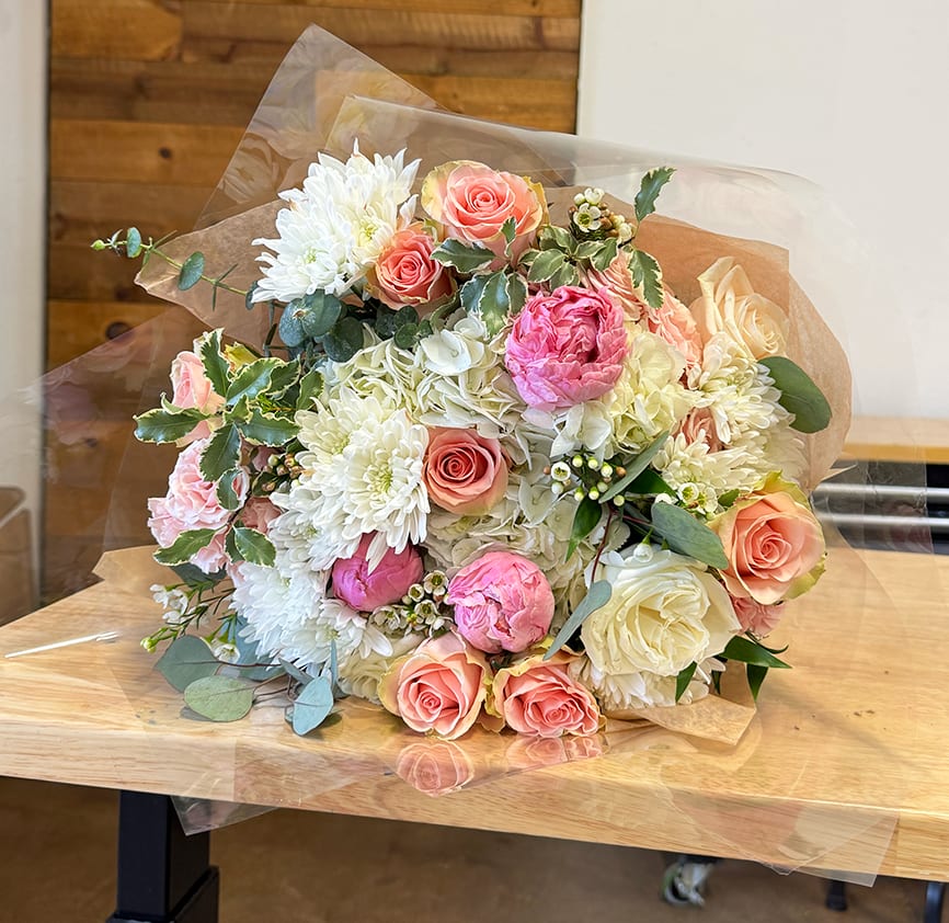 Bouquet of pink and white roses with white chrysanthemums wrapped in clear paper