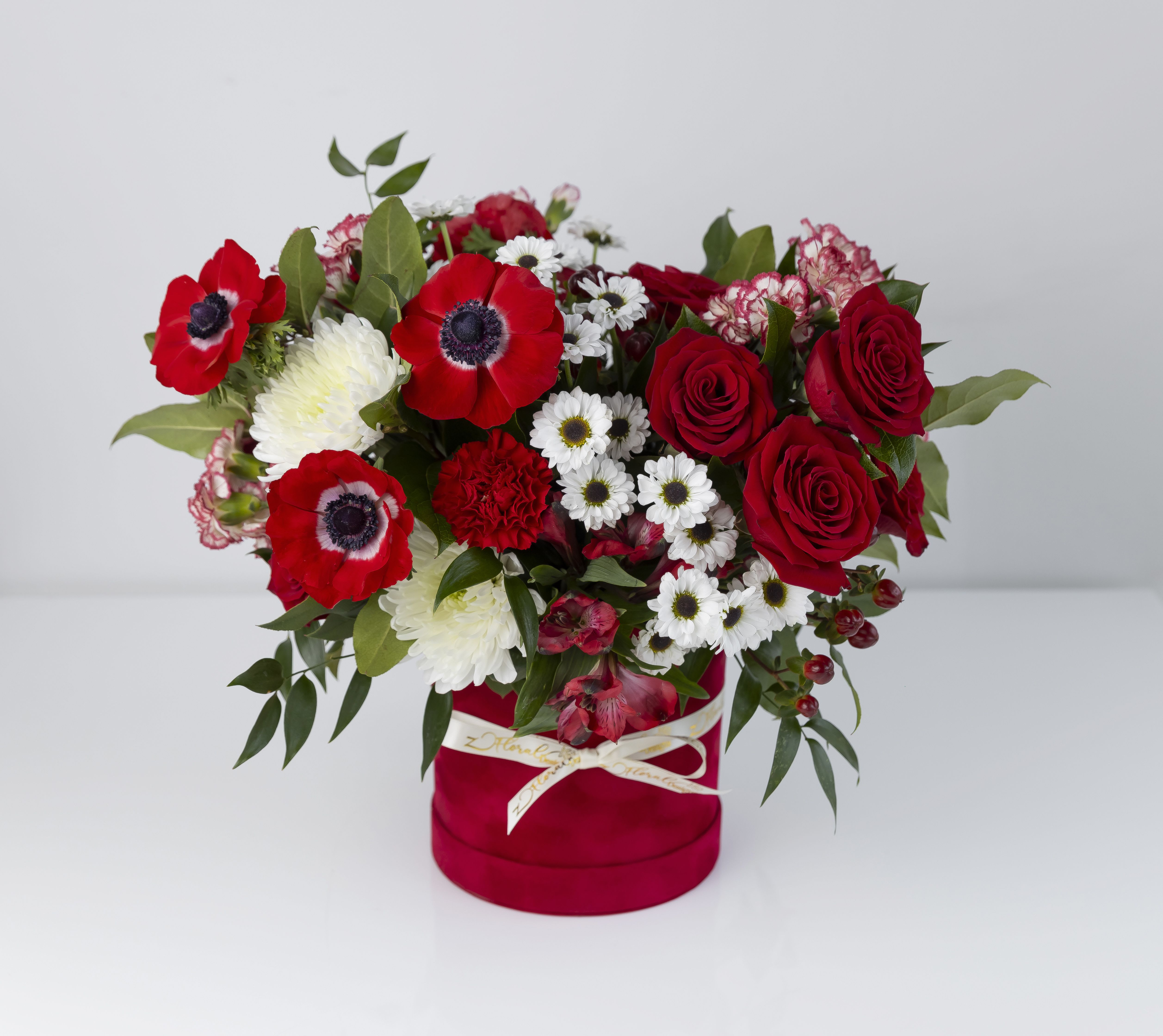 Crimson Romance Box - A bold and passionate arrangement designed to captivate. Featuring rich red roses, striking anemones, delicate white blooms, and textured carnations, this design is beautifully arranged in a luxurious velvet box. Accented with greenery, it creates a perfect balance of drama and elegance. Ideal for this Mother's Day or any special occation such as anniversaries, or making a powerful statement of love and admiration. 