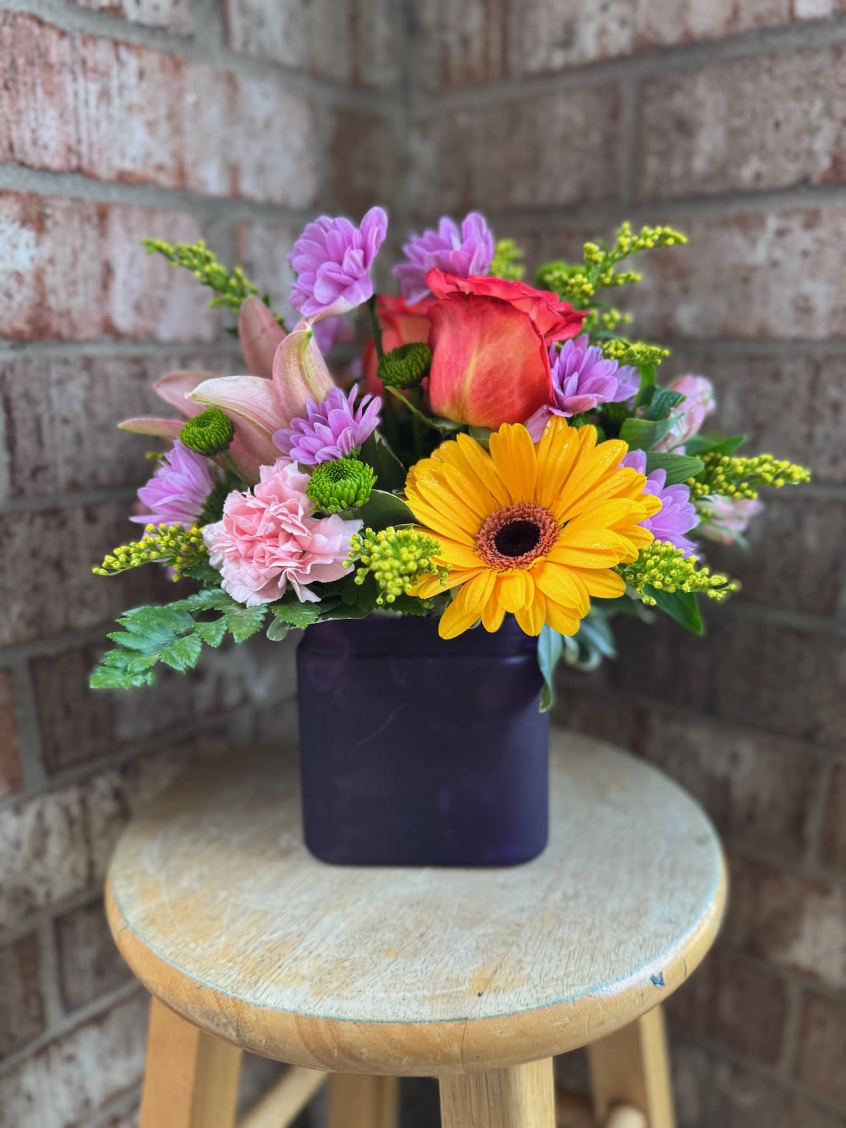 Mixed bouquet in a dark square vase with a yellow gerbera and pink rose