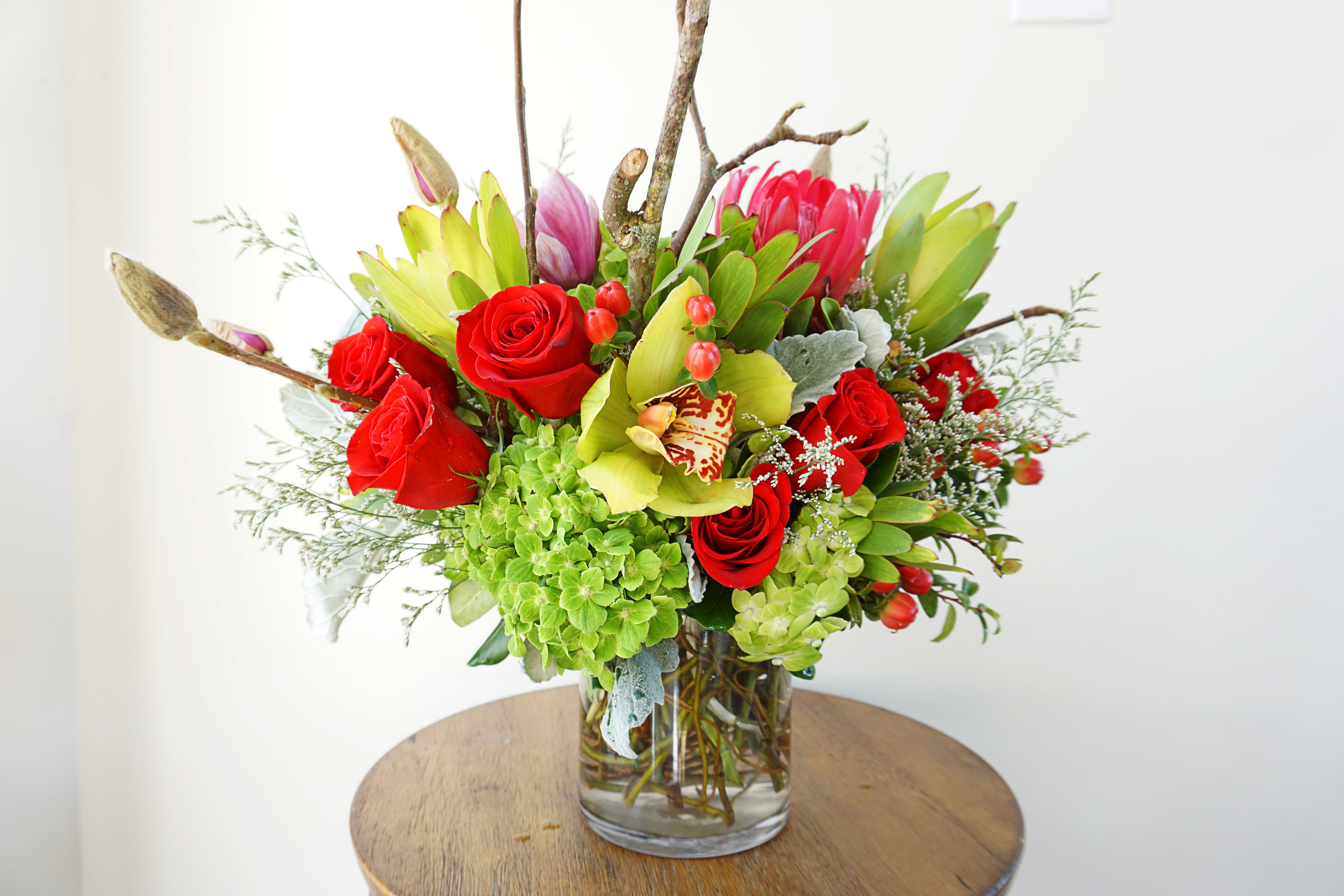 Bouquet of red roses and green blooms in a clear glass vase