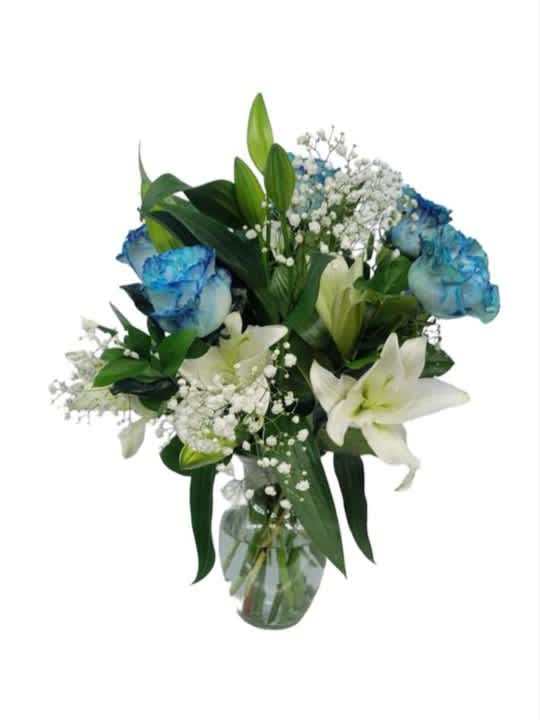 Bouquet of white lilies and blue-tinted roses in a glass vase