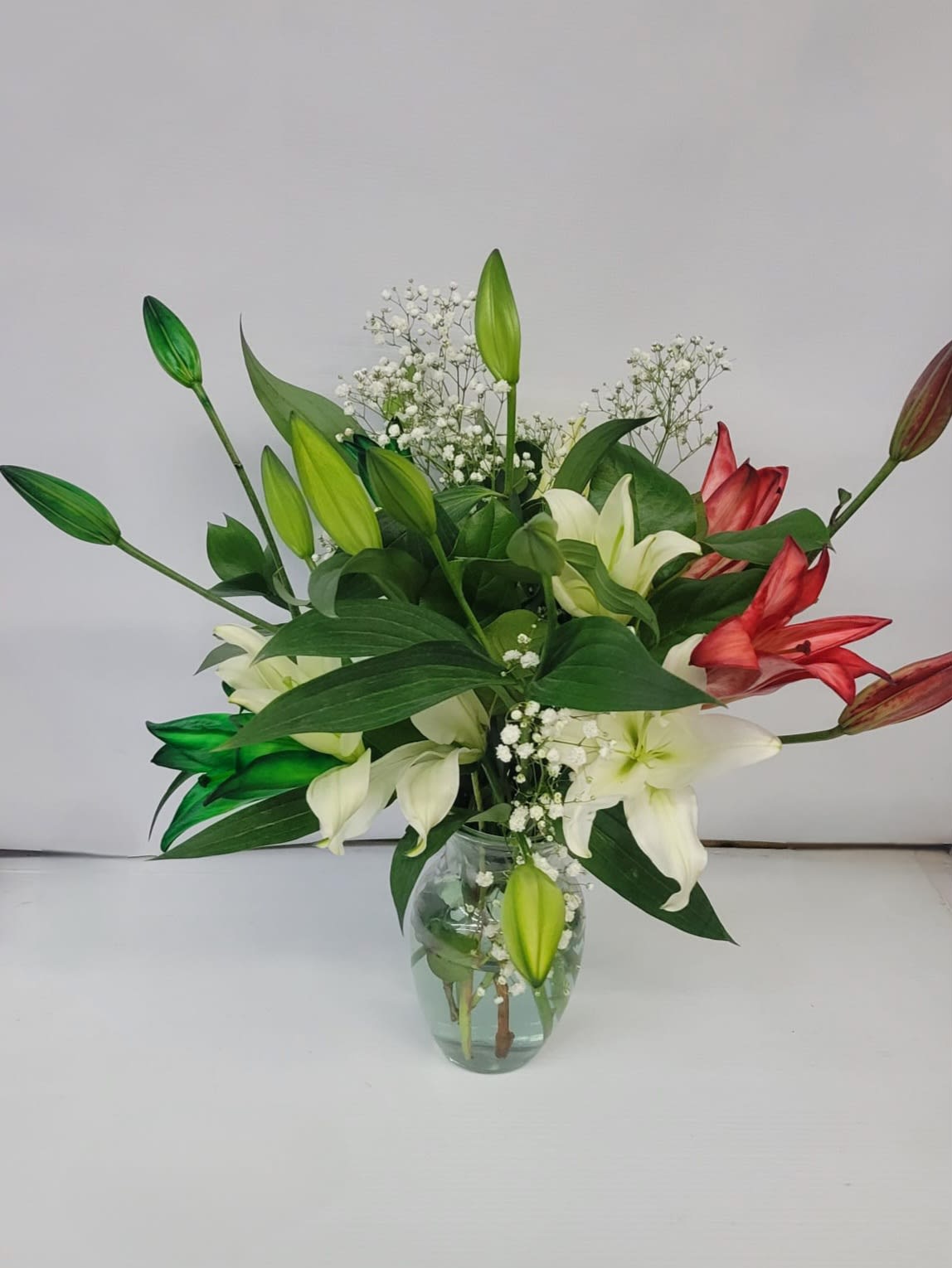 Bouquet of white and red lilies in a clear glass vase