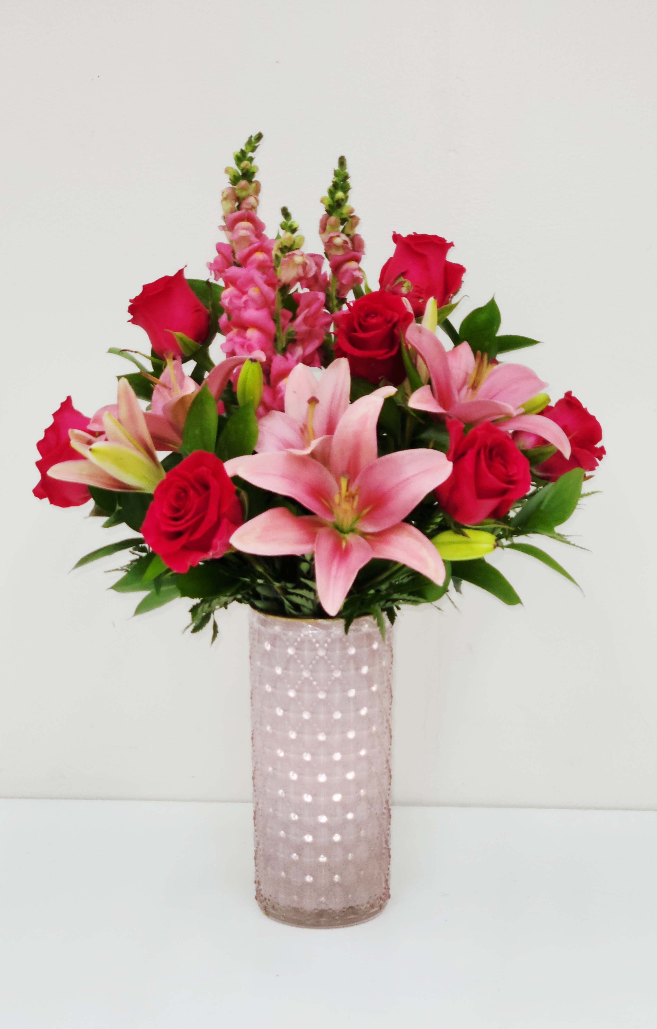 Lovely You - Large size lush mix of pink lilies, red roses, and tall snapdragons in a pink textured glass vase, fuller height and volume with more flowers added.