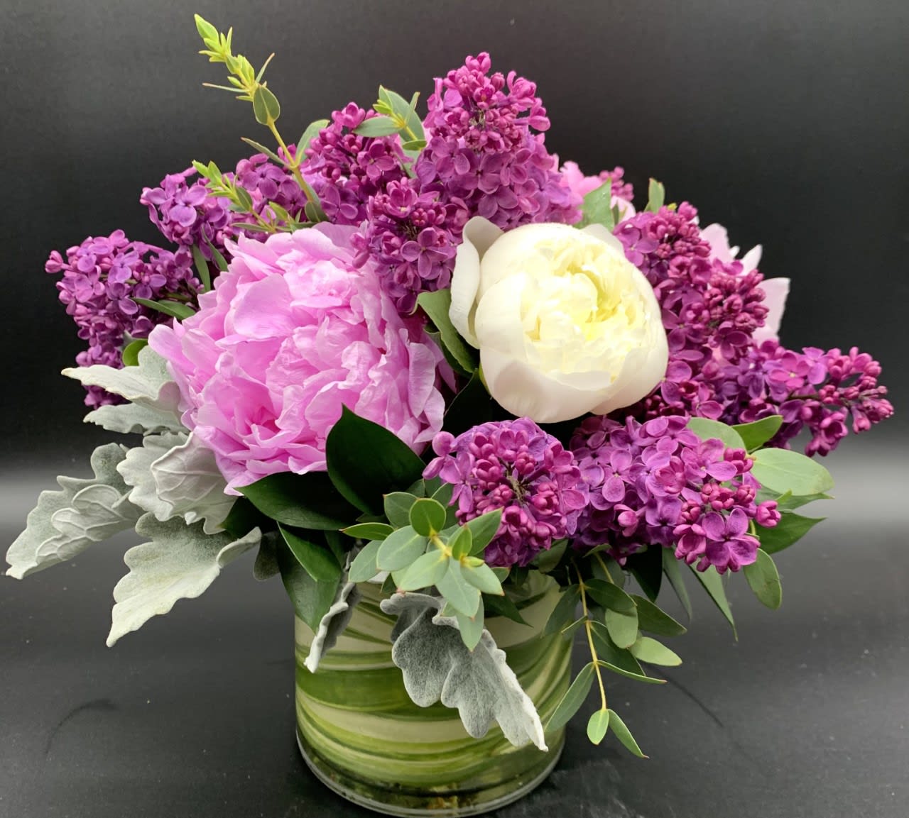 Pink and white flowers arranged in a glass vase with purple blooms