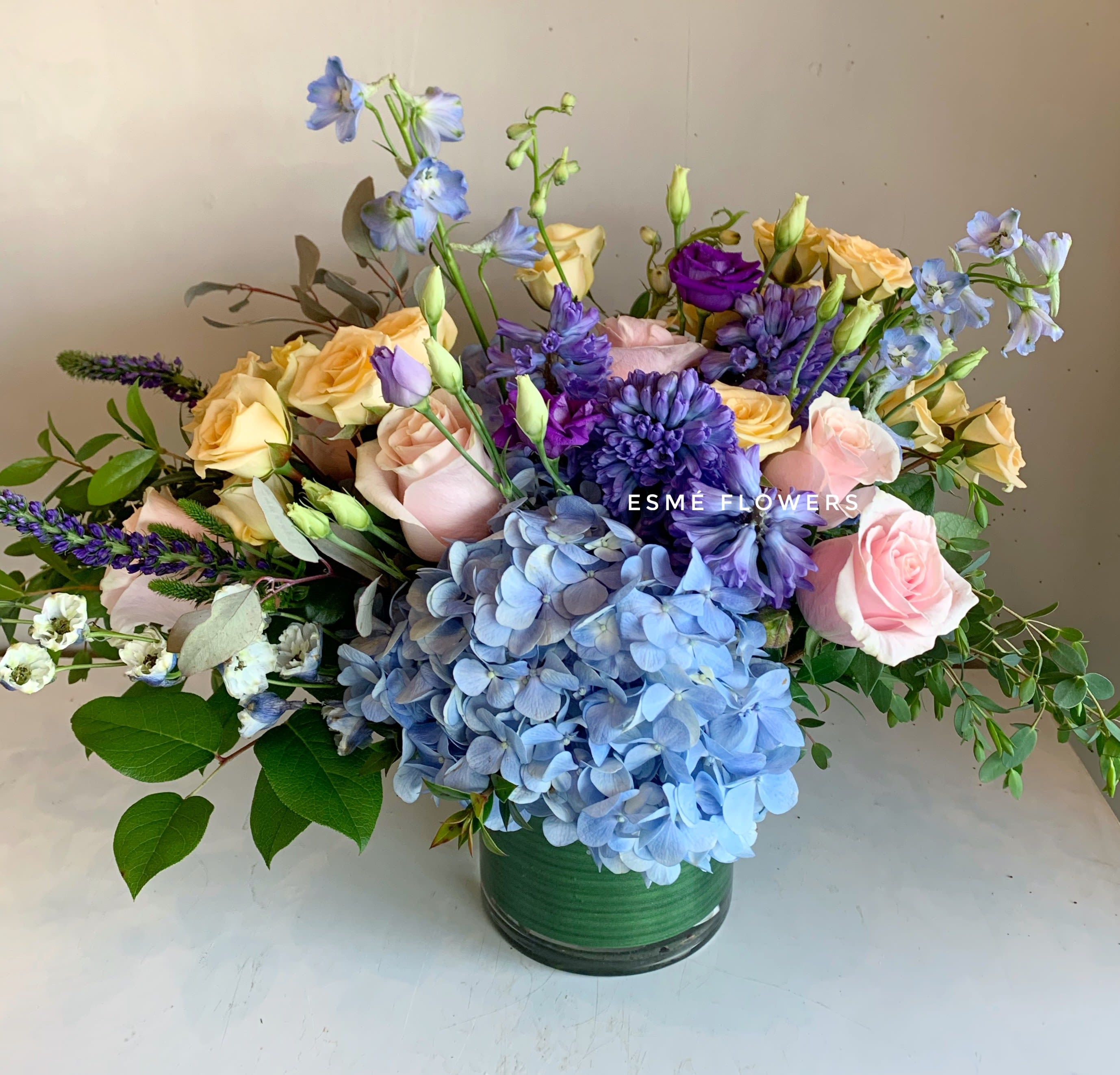Bluebells - A beautiful combination of blue hyacinth from Holland, lush blue hydrangea and soft pink and peach roses.  AVAILABLE STARTING MOTHER'S DAY WEEK 5/4