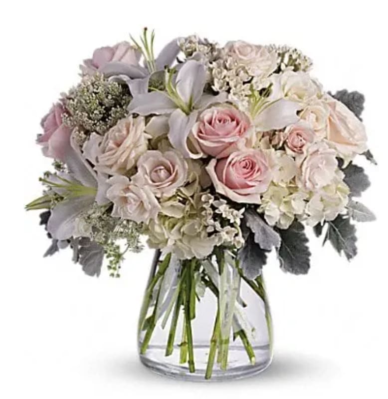 Blush and white bouquet of roses and lilies in a clear glass vase