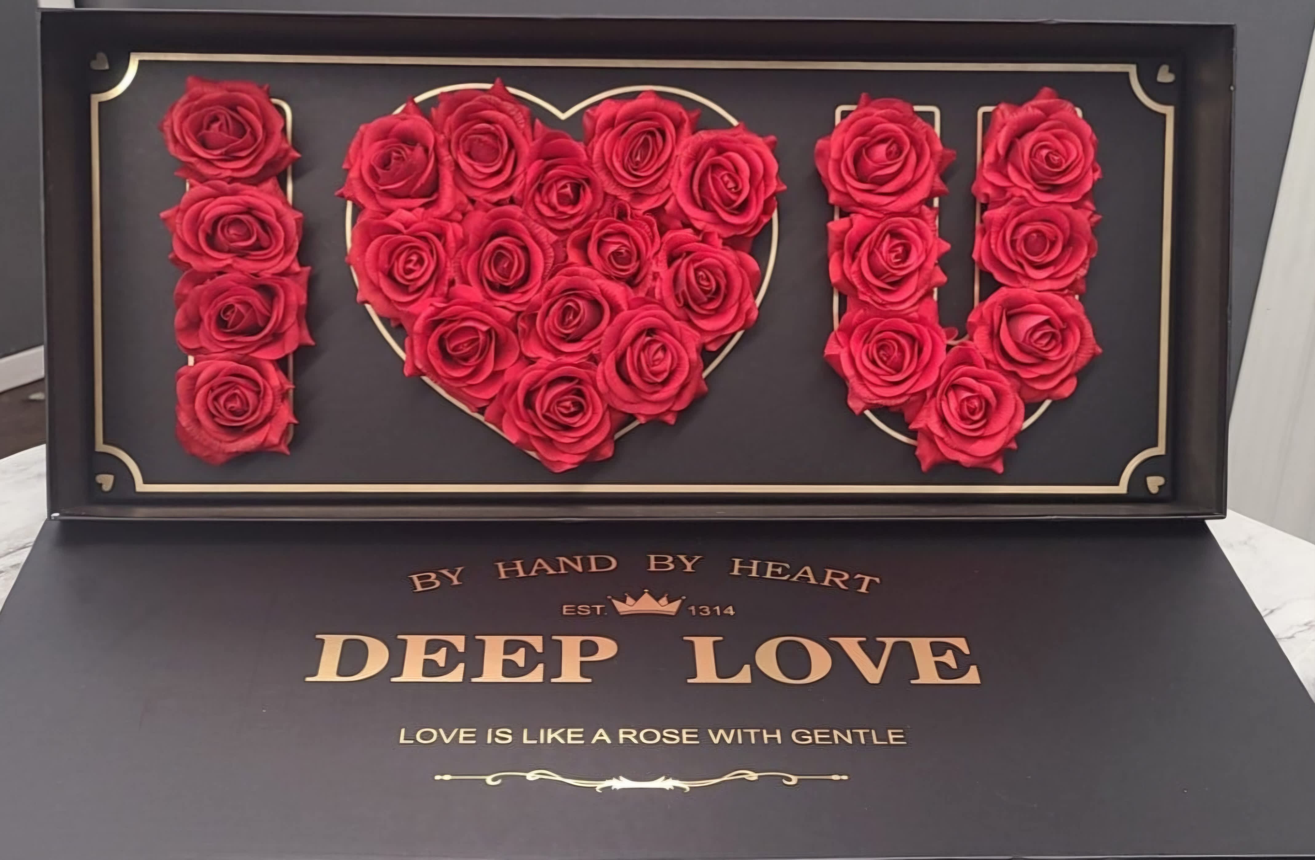 Red roses arranged to spell I heart U in a black display box