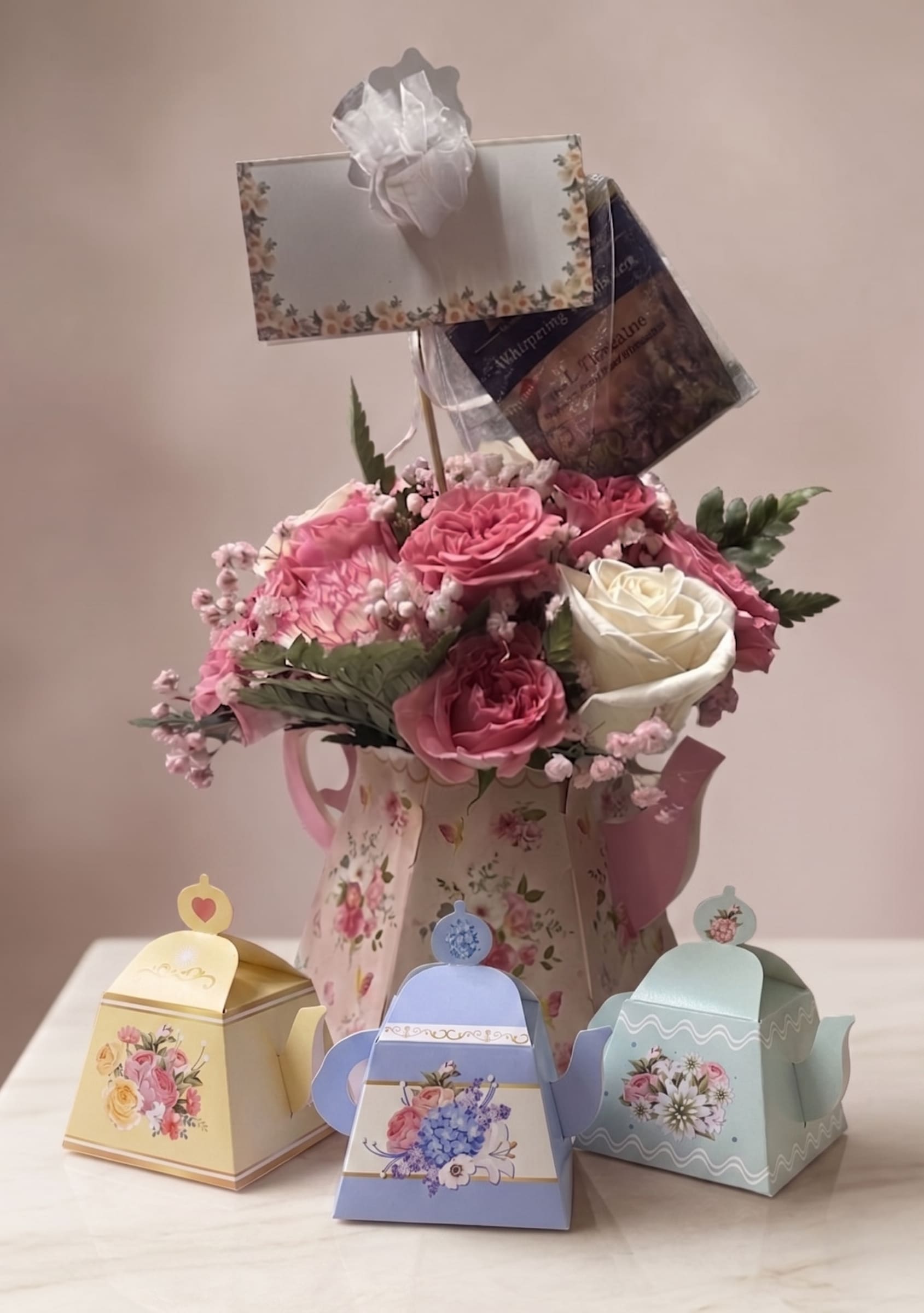 The "Sweetest Tea" Floral &amp; Candy Set - A delightful Mother's Day gift set featuring a large, vintage-inspired floral paper teapot filled with Pink Carnations, Mauve Roses, and Ivory Roses. This complete set includes a beautiful blend of Fresh Blooms, Tea Bag, and Tea Time inspired Box of Candy