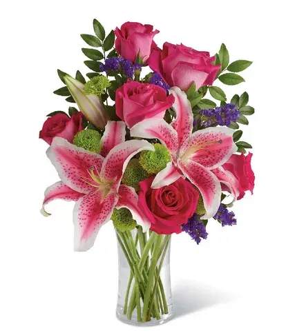 Pink roses and lilies arranged in a clear glass vase