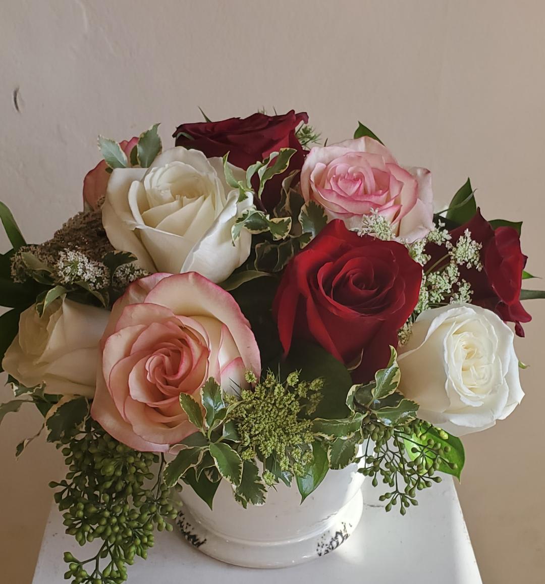 Bouquet of red, white, and pink roses in a white vase