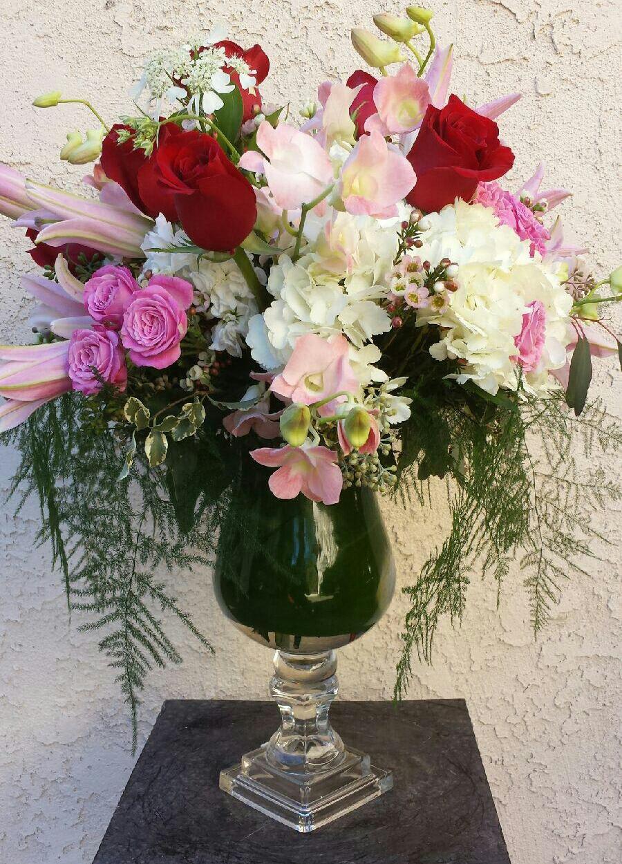Mixed bouquet of red roses, pink orchids, and white hydrangeas in a glass vase