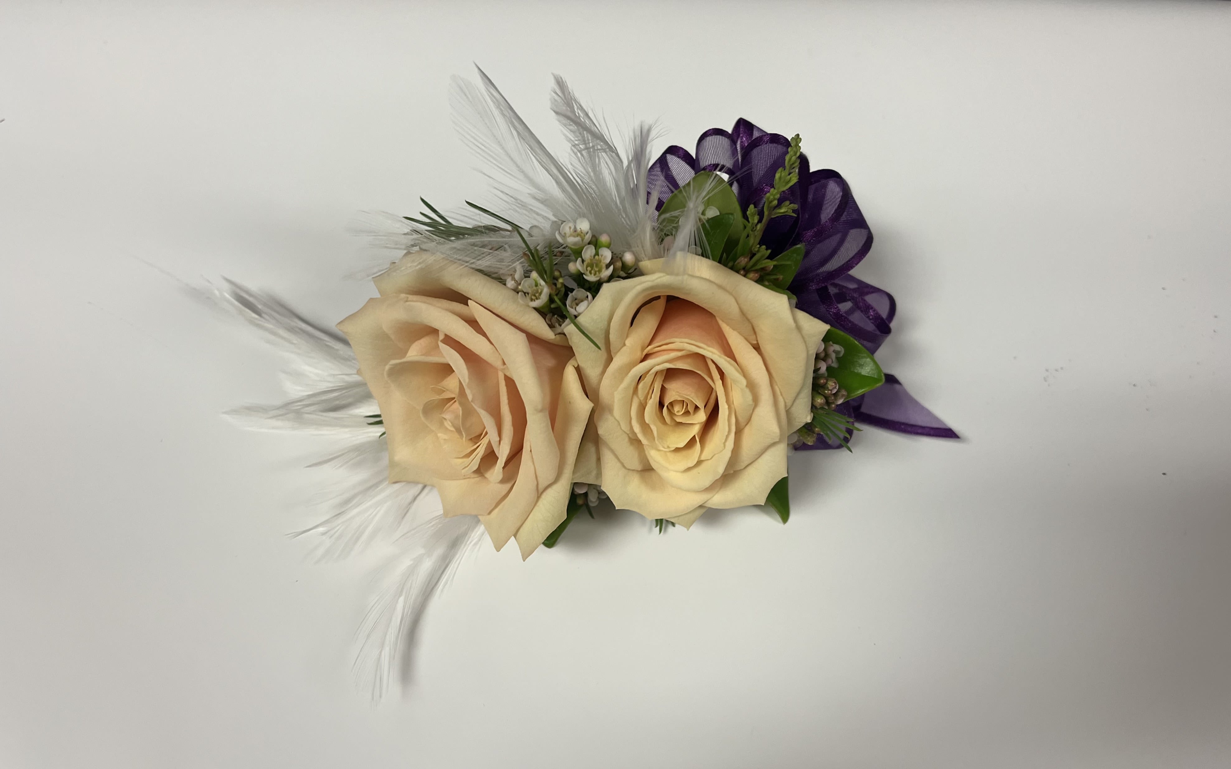 Two cream roses with purple ribbon and white feathers